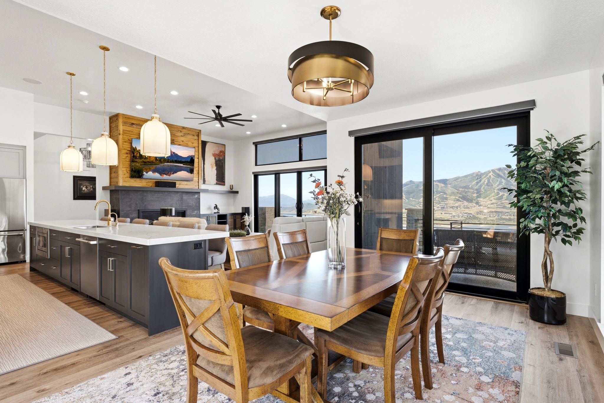 Open-concept dining area with wood-finish flooring, a contemporary chandelier, and a sliding glass door
