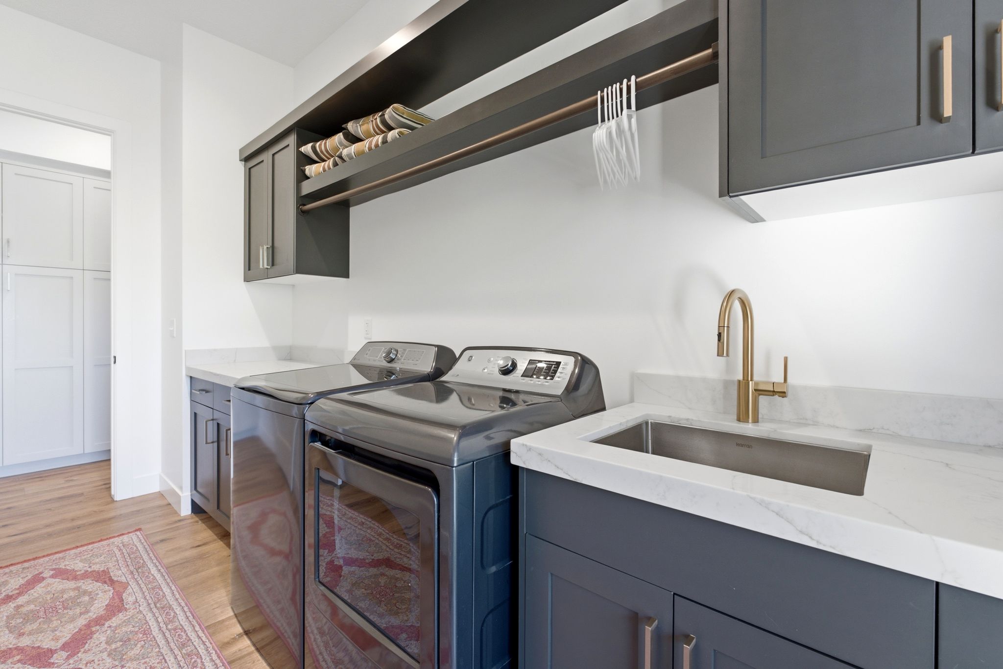 Dedicated laundry room featuring wood-finish flooring and white walls