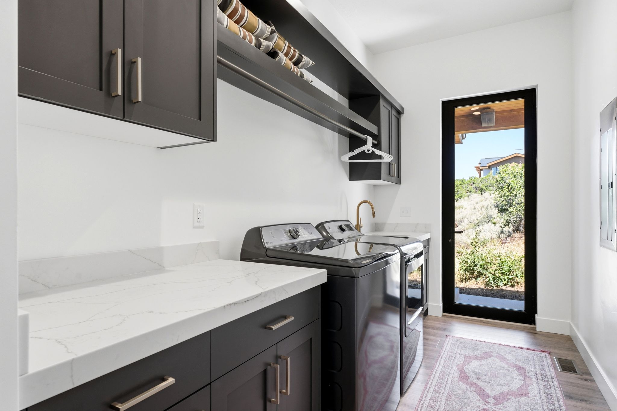 Laundry room featuring dark wood-finish cabinetry, white stone countertops, and wood-finish flooring