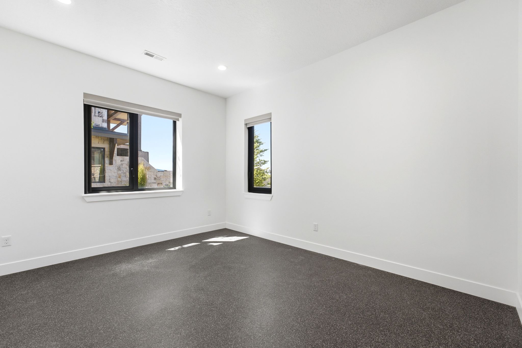 Spacious room featuring neutral walls, dark carpeting, and recessed lighting