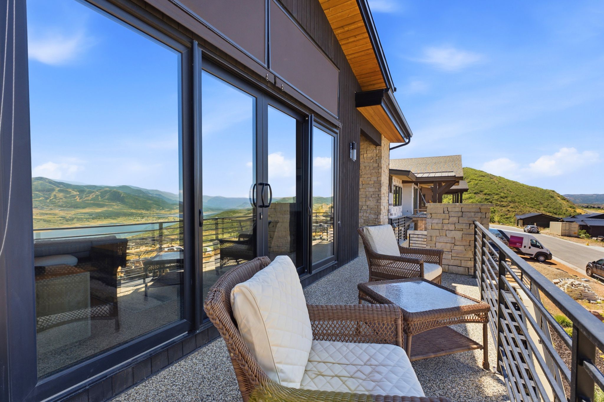 Expansive outdoor balcony featuring a stone privacy wall, metal railing, and a textured concrete surface