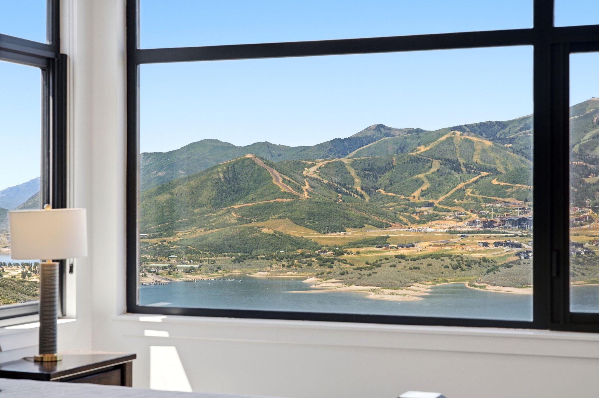 Expansive windows frame a mountain and lake landscape