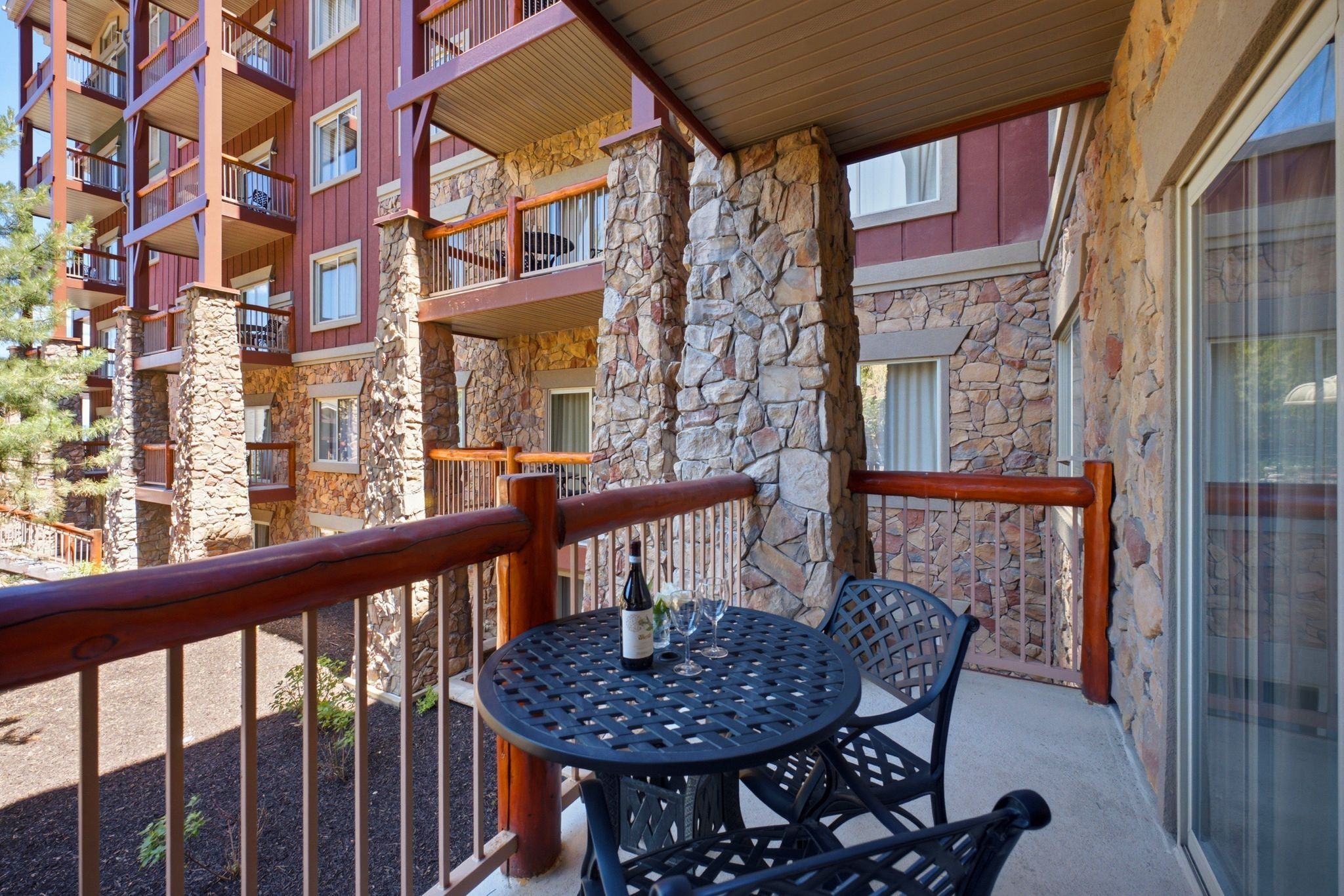 Private balcony featuring log-style railings and stone veneer pillars