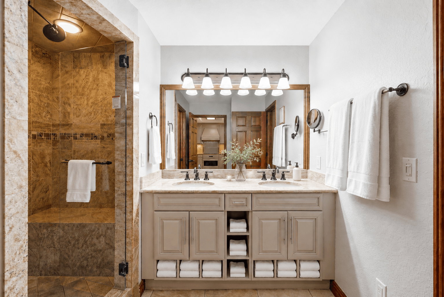 Dual sink vanity with stone countertop, built-in storage, and framed mirror