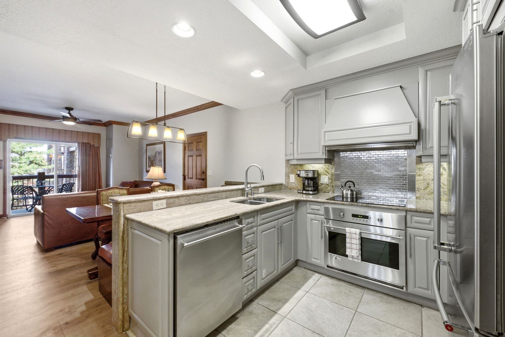 Modern kitchen featuring gray cabinetry, granite countertops, and stainless steel appliances