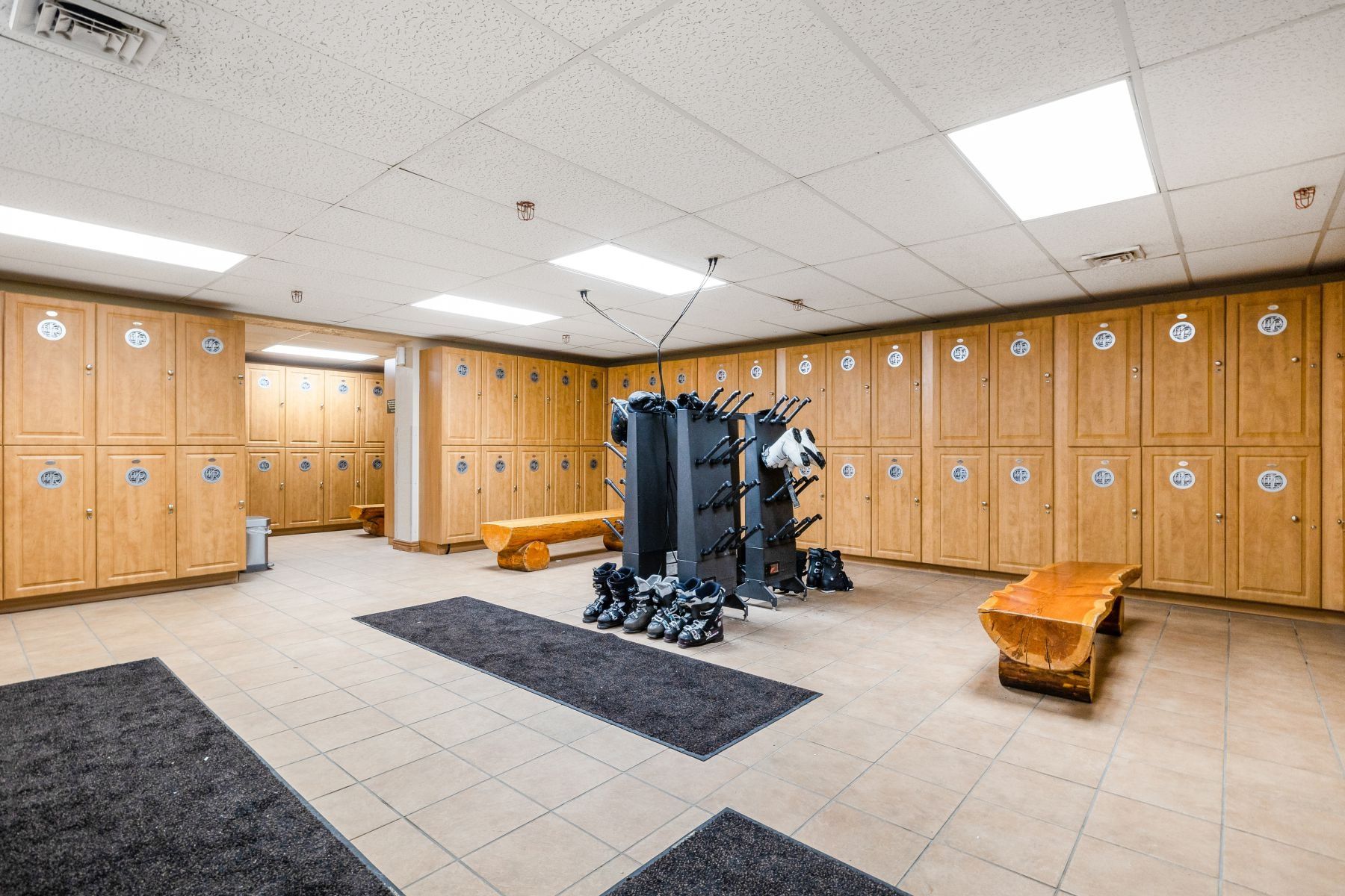 Locker room featuring extensive wood-finish cabinetry, tile flooring, and integrated overhead lighting