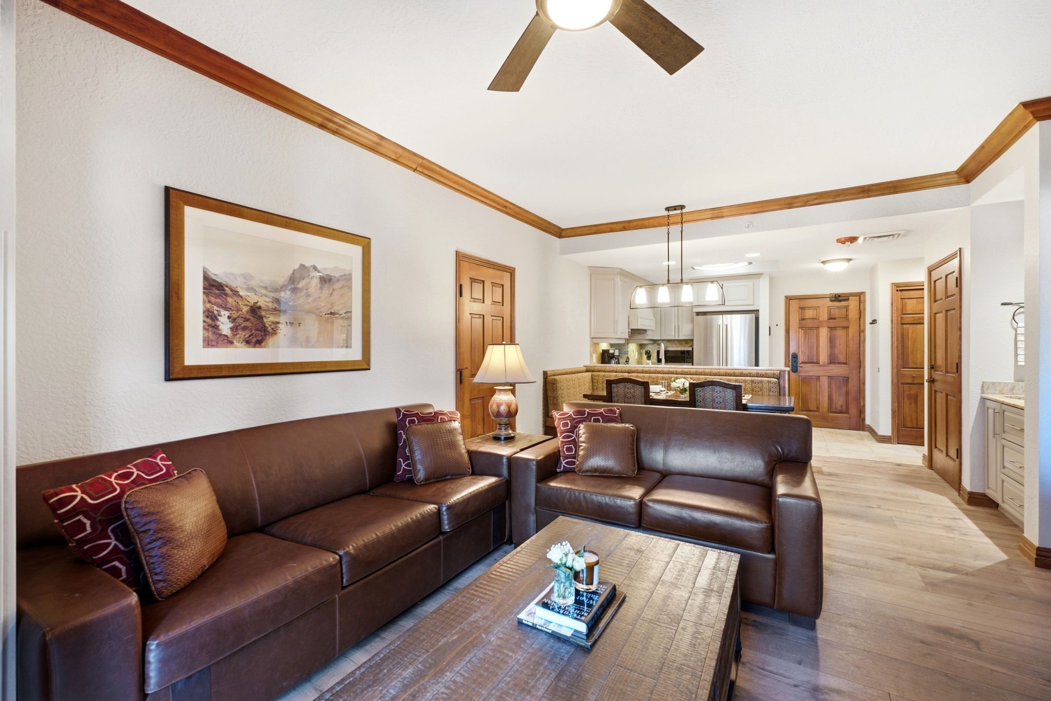 Open-concept living space with wood-finish flooring, crown molding, and a ceiling fan