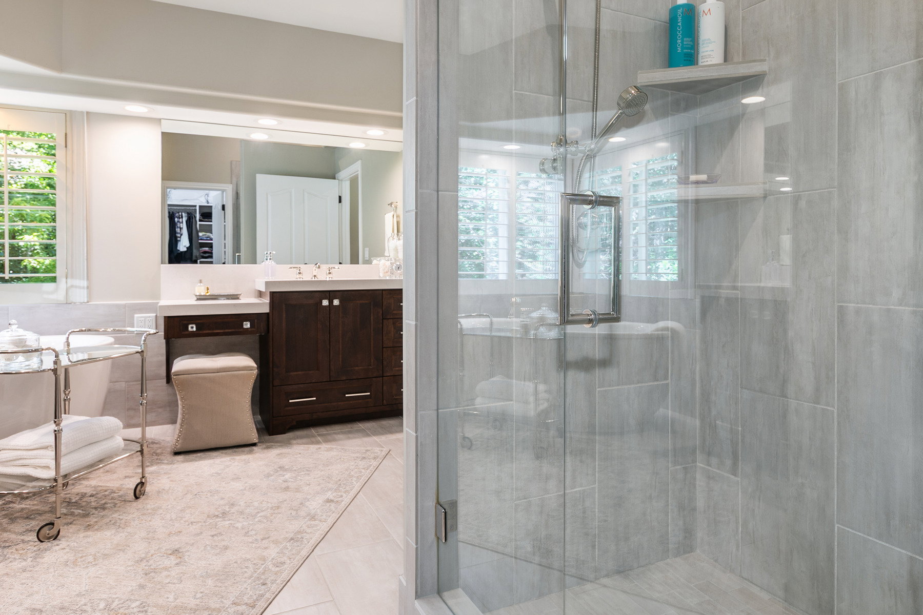 Glass-enclosed shower featuring large format tile and a built-in corner shelf in primary bathroom
