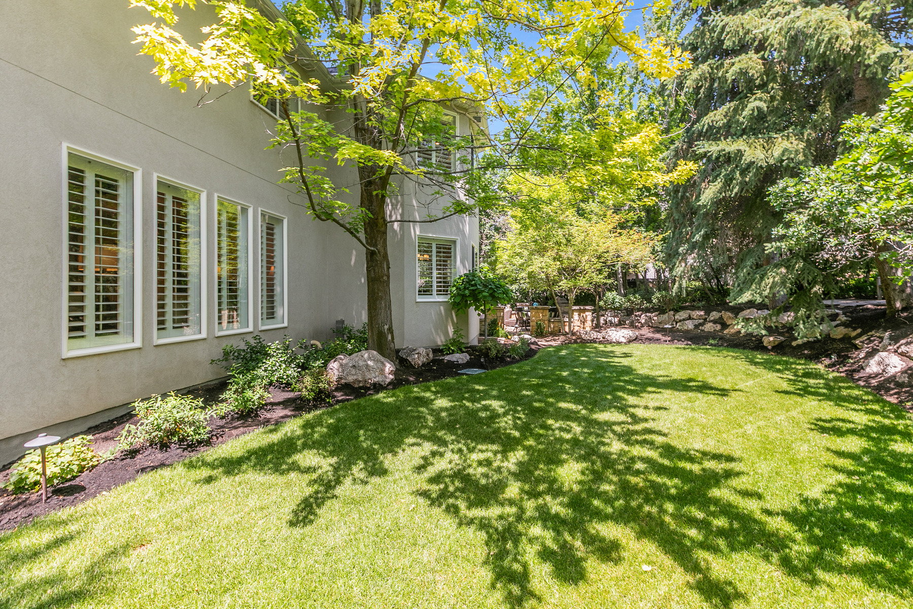 Lush green lawn with mature trees and landscaped planting beds