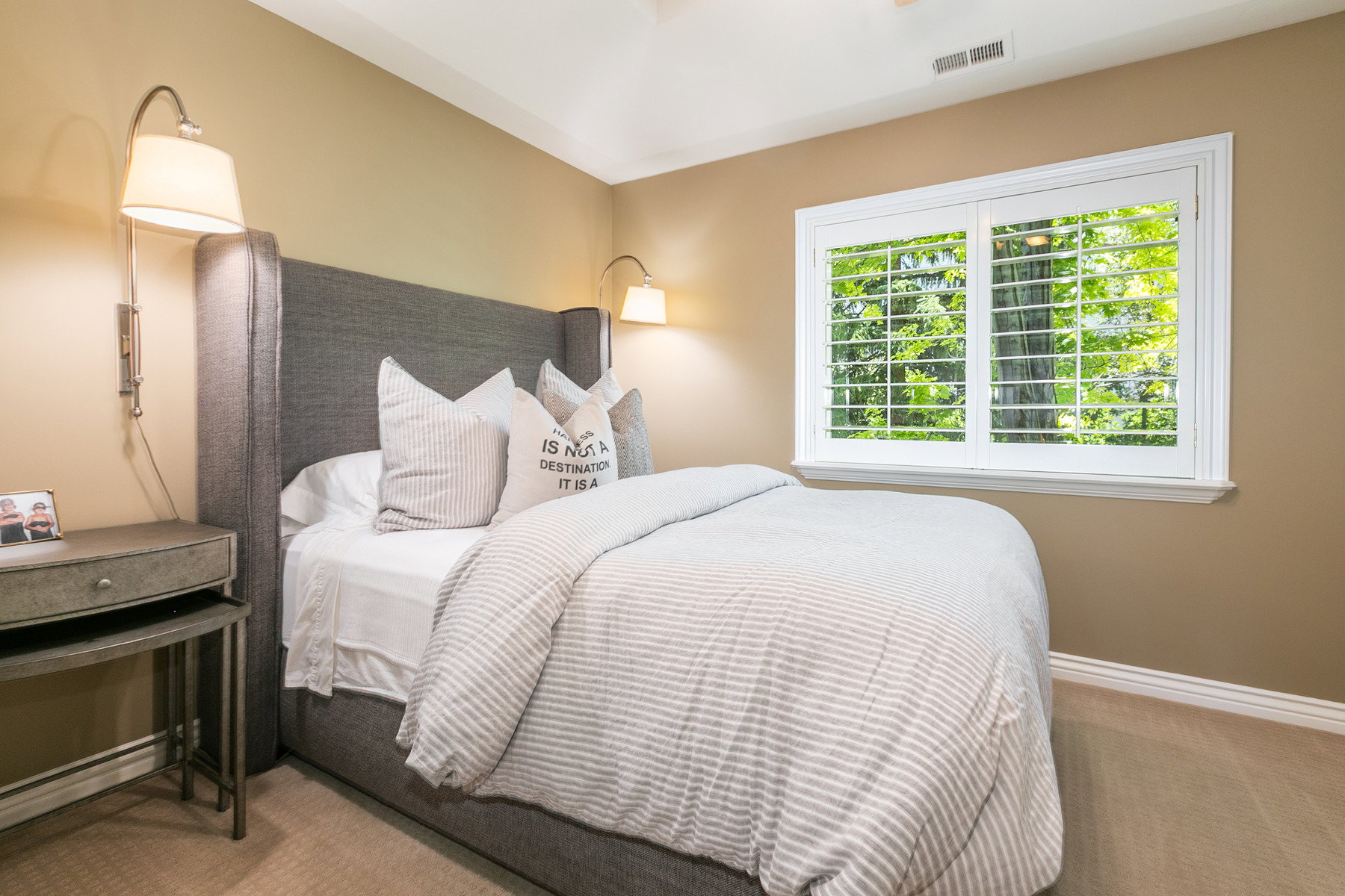 Inviting room featuring a window with white louvered shutters, neutral-toned wall paint, and plush carpeting