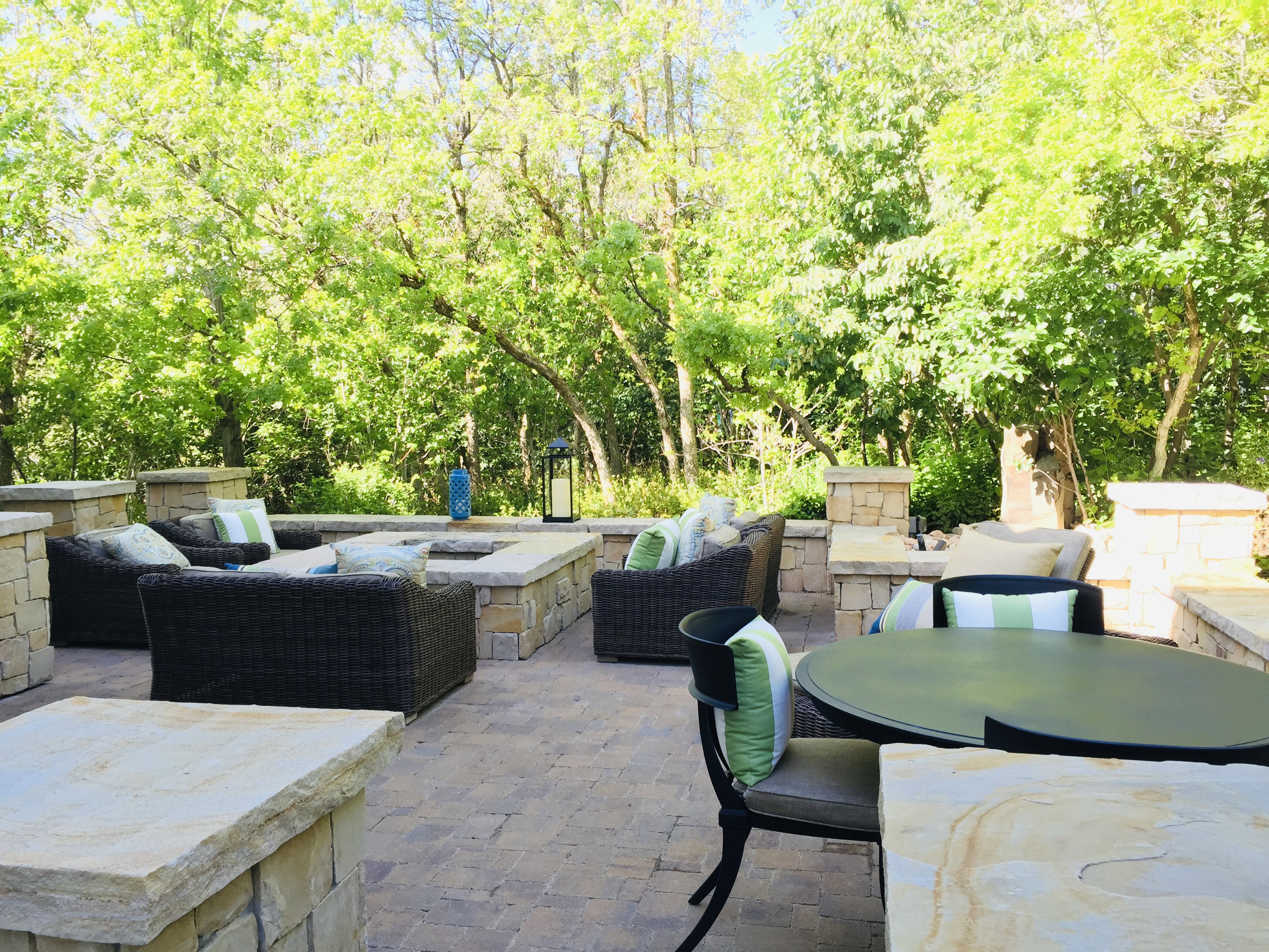 Spacious outdoor patio featuring paver flooring, natural stone retaining walls, and a built-in stone fire pit
