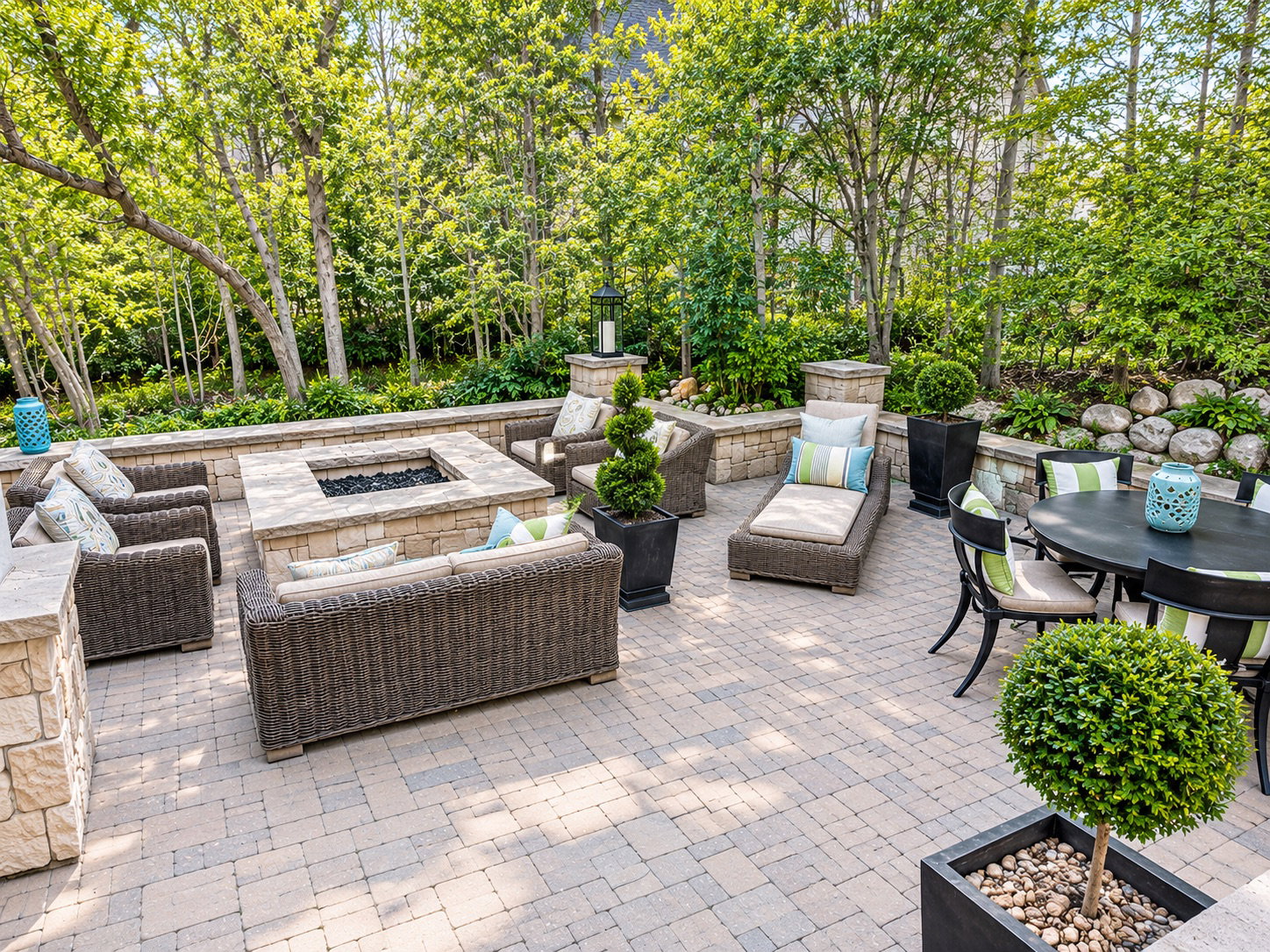 Expansive paver patio featuring a built-in stone fire pit, extensive retaining walls, and mature landscaping