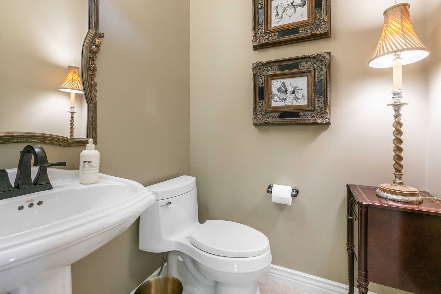 Powder room featuring a pedestal sink with a dark bronze faucet, a white toilet, and neutral wall paint