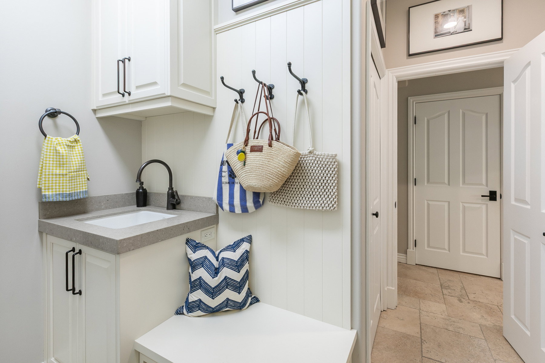 Utility area with a built-in bench, white cabinetry, and a sink with a dark-finish faucet