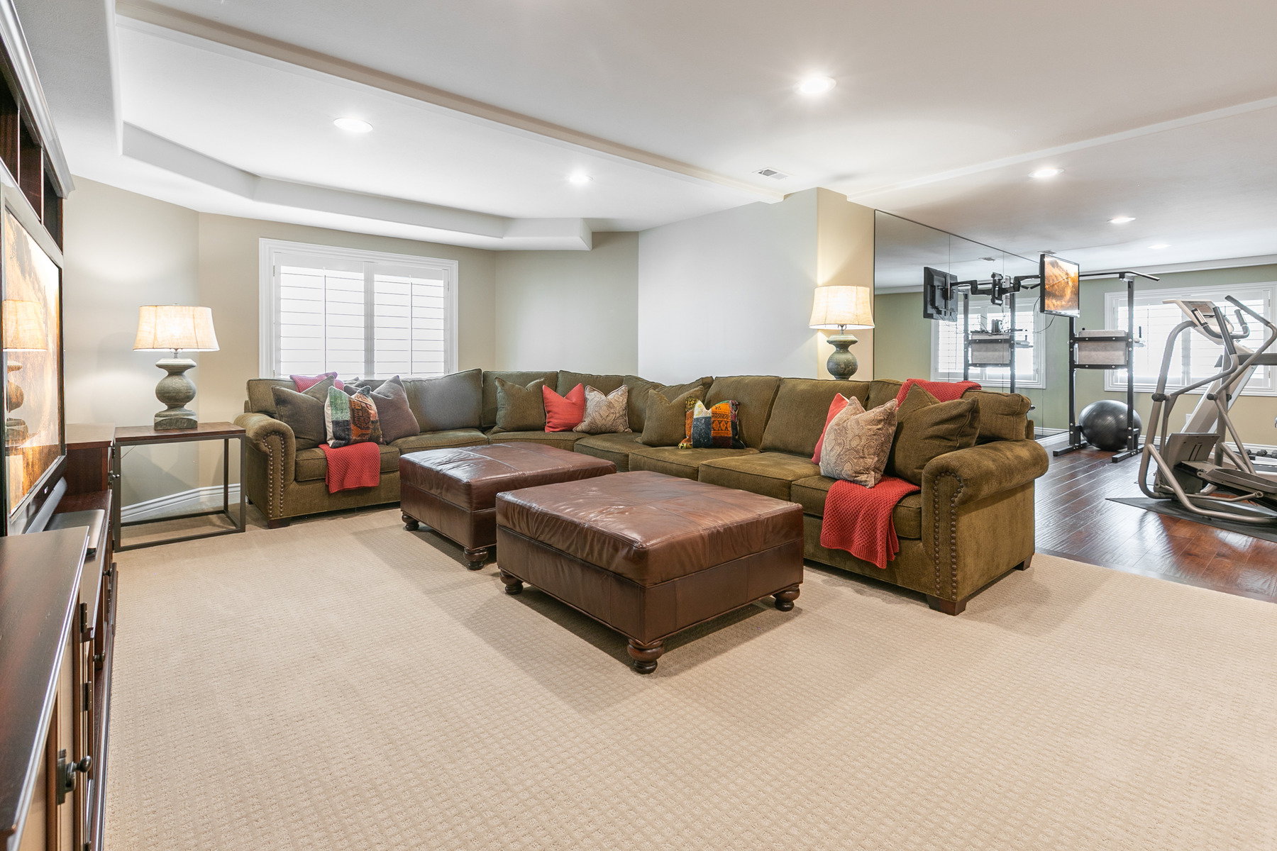 Spacious entertainment area featuring recessed lighting, a coffered ceiling detail, and a large window with plantation shutters
