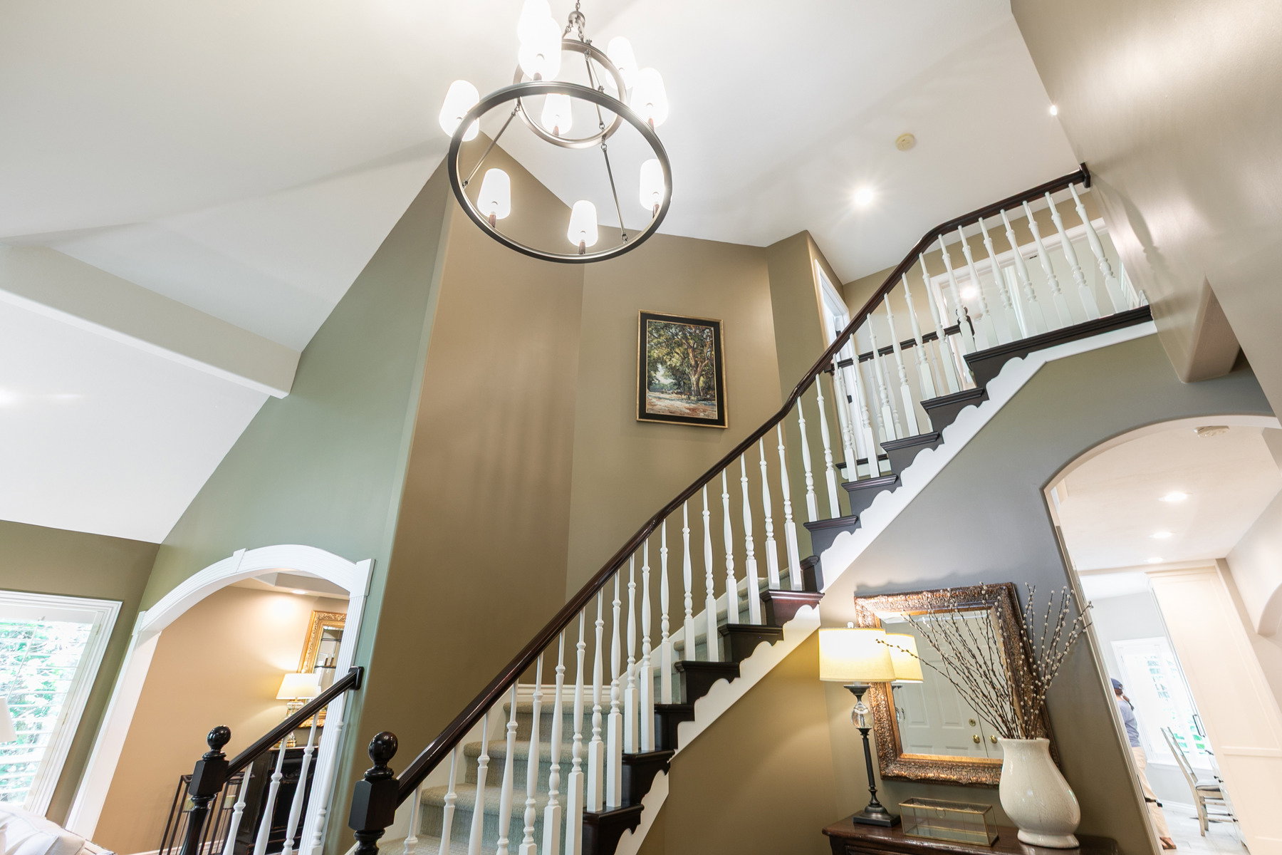 Two-story foyer featuring a grand staircase with dark wood-finish treads and white balusters