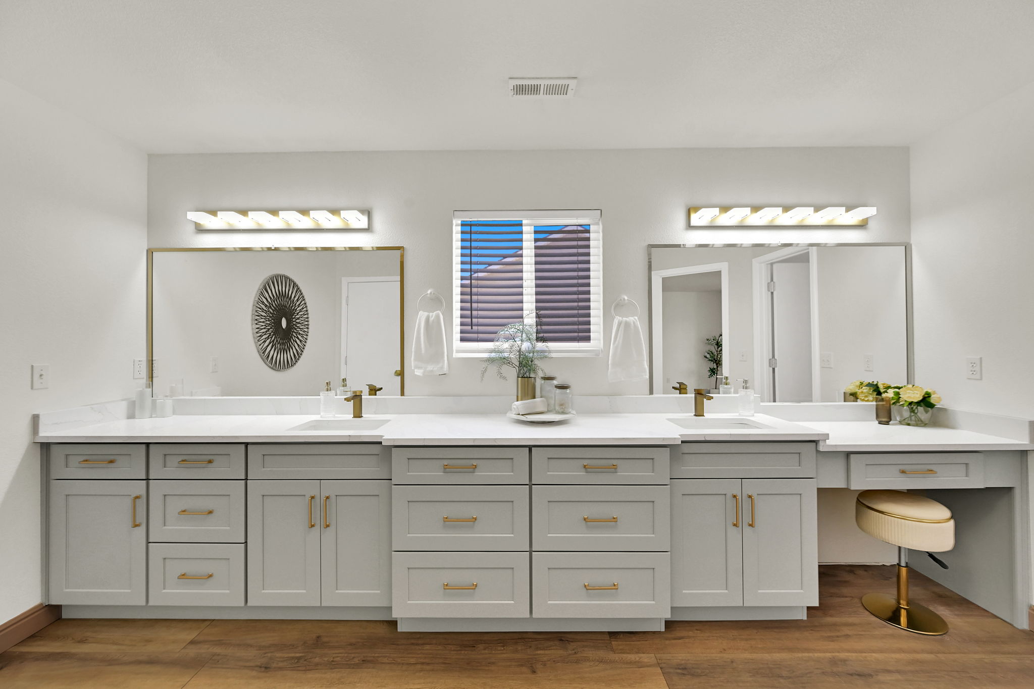 Bathroom featuring 15 foot vanity with dual sinks and  seamless dressing vanity with white Quartz countertops, light gray cabinetry, and gold-finish hardware