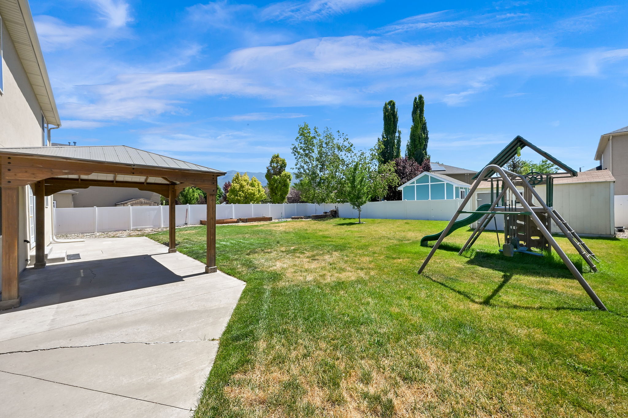 PERGOLA Expansive backyard featuring a covered patio with wood supports and a concrete slab, a manicured lawn, and a white privacy fence