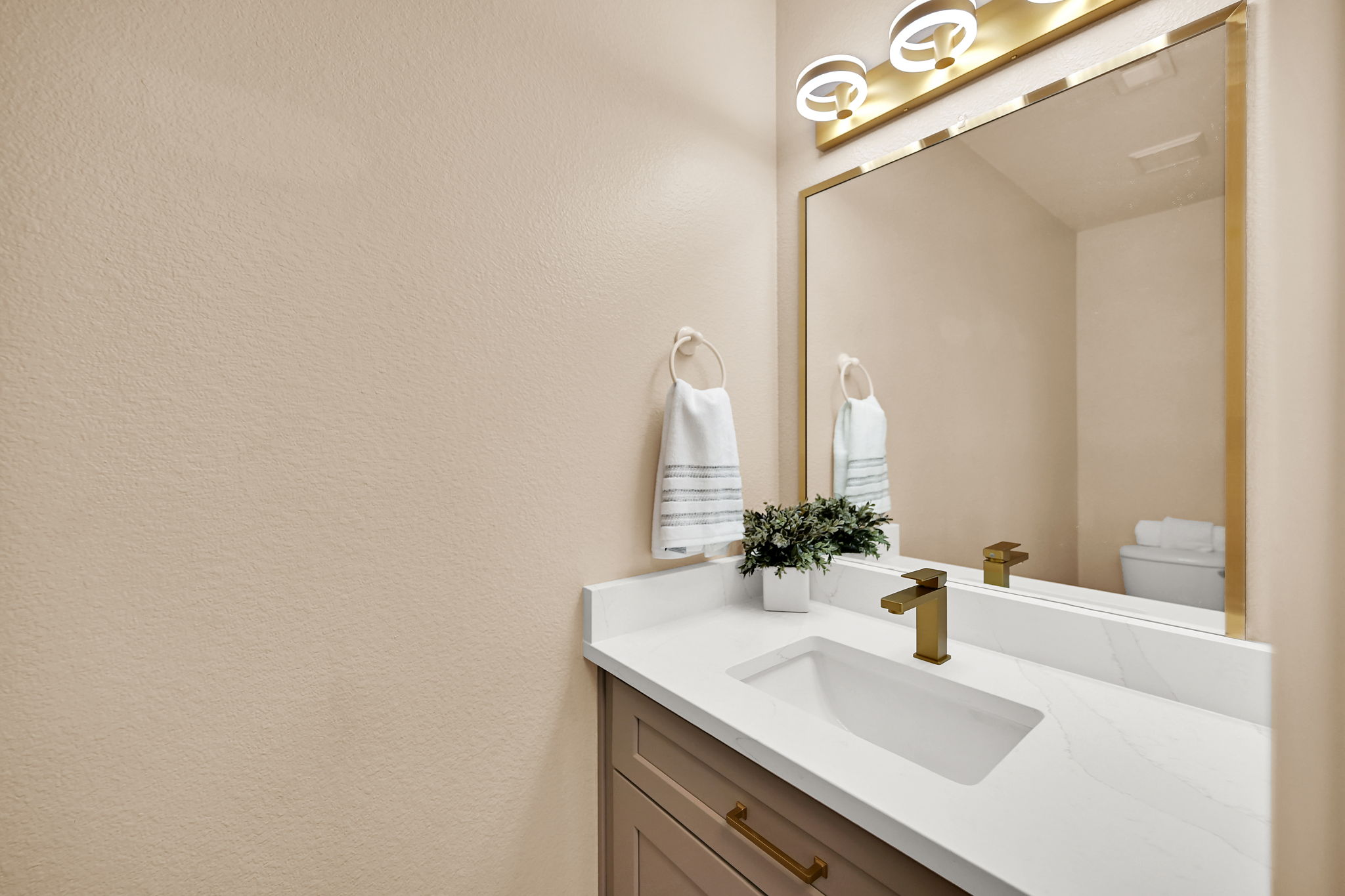 Vanity with a white countertop and integrated sink, featuring a gold-toned faucet and cabinet hardware