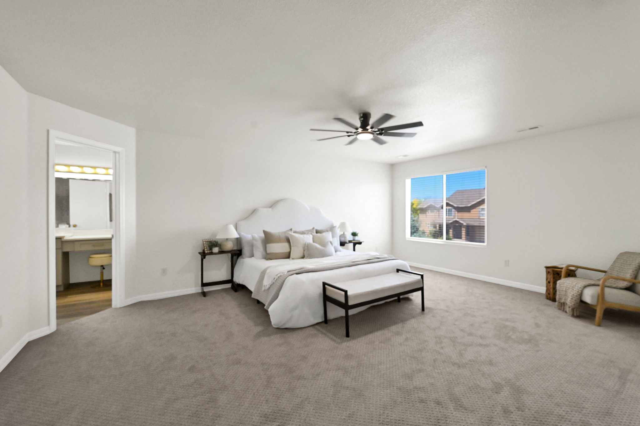 Spacious primary bedroom featuring modern patterned warm sand color carpeting, a picture window, and a dark-toned ceiling fan