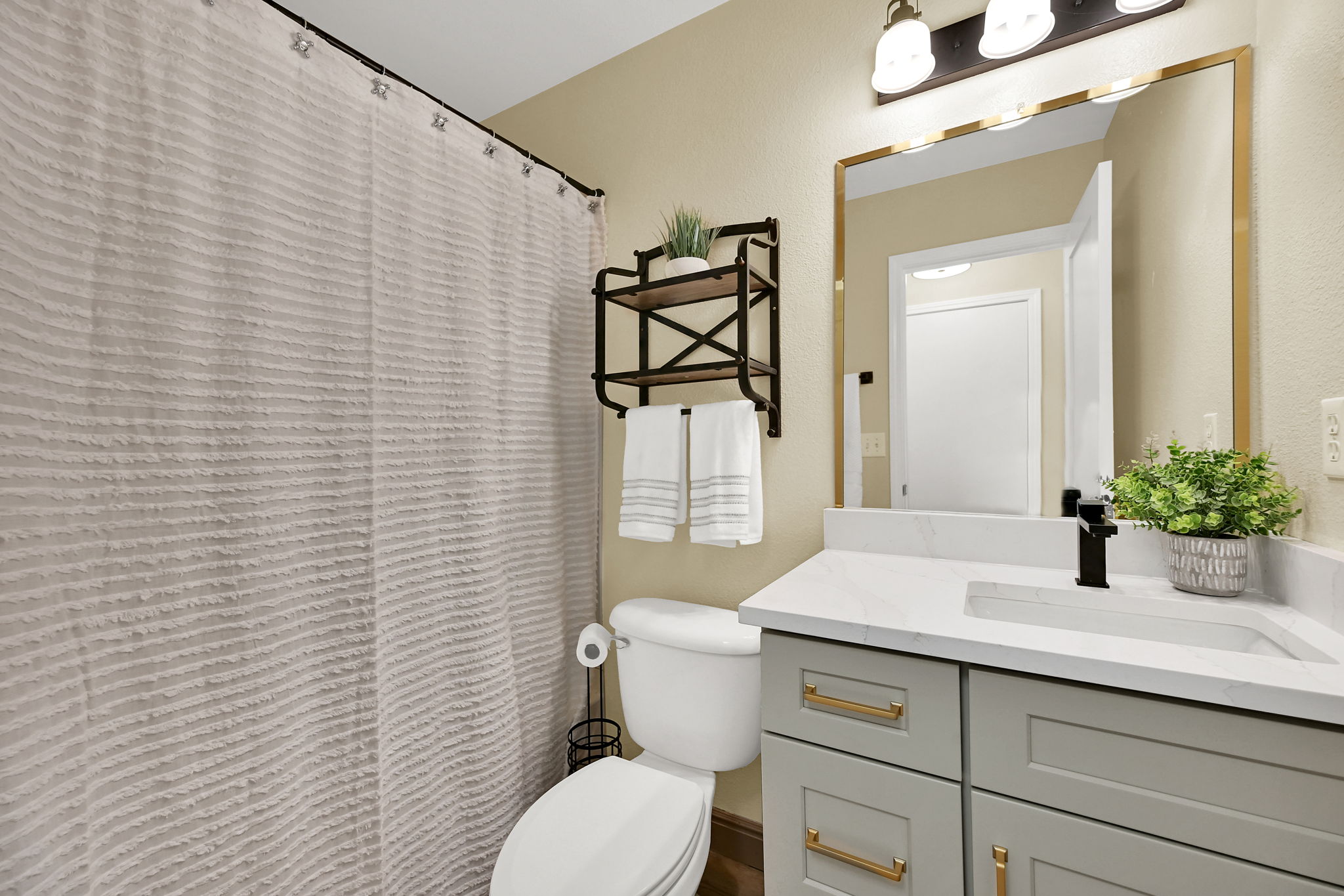 Bathroom featuring a gray vanity with gold hardware, white quartz countertop, and a rectangular undermount sink