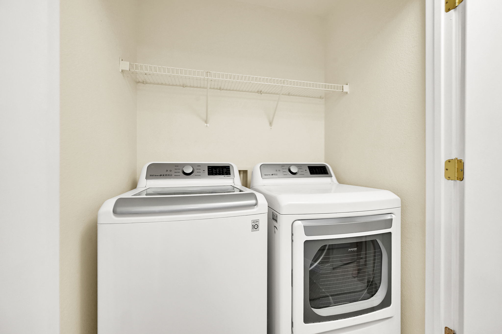 Dedicated laundry area featuring a top-load washing machine, front-load dryer, and overhead wire shelving