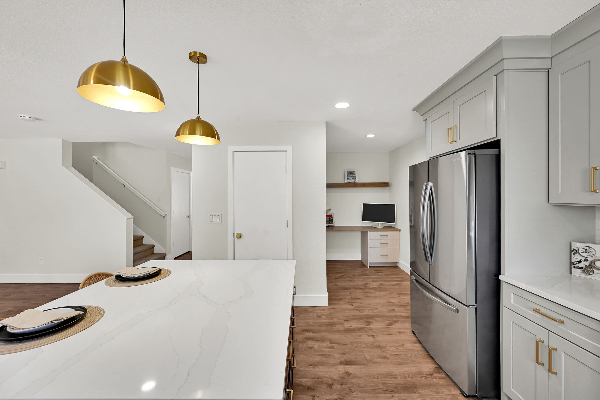 Kitchen island with a white quartz countertop, complemented by gold pendant lighting