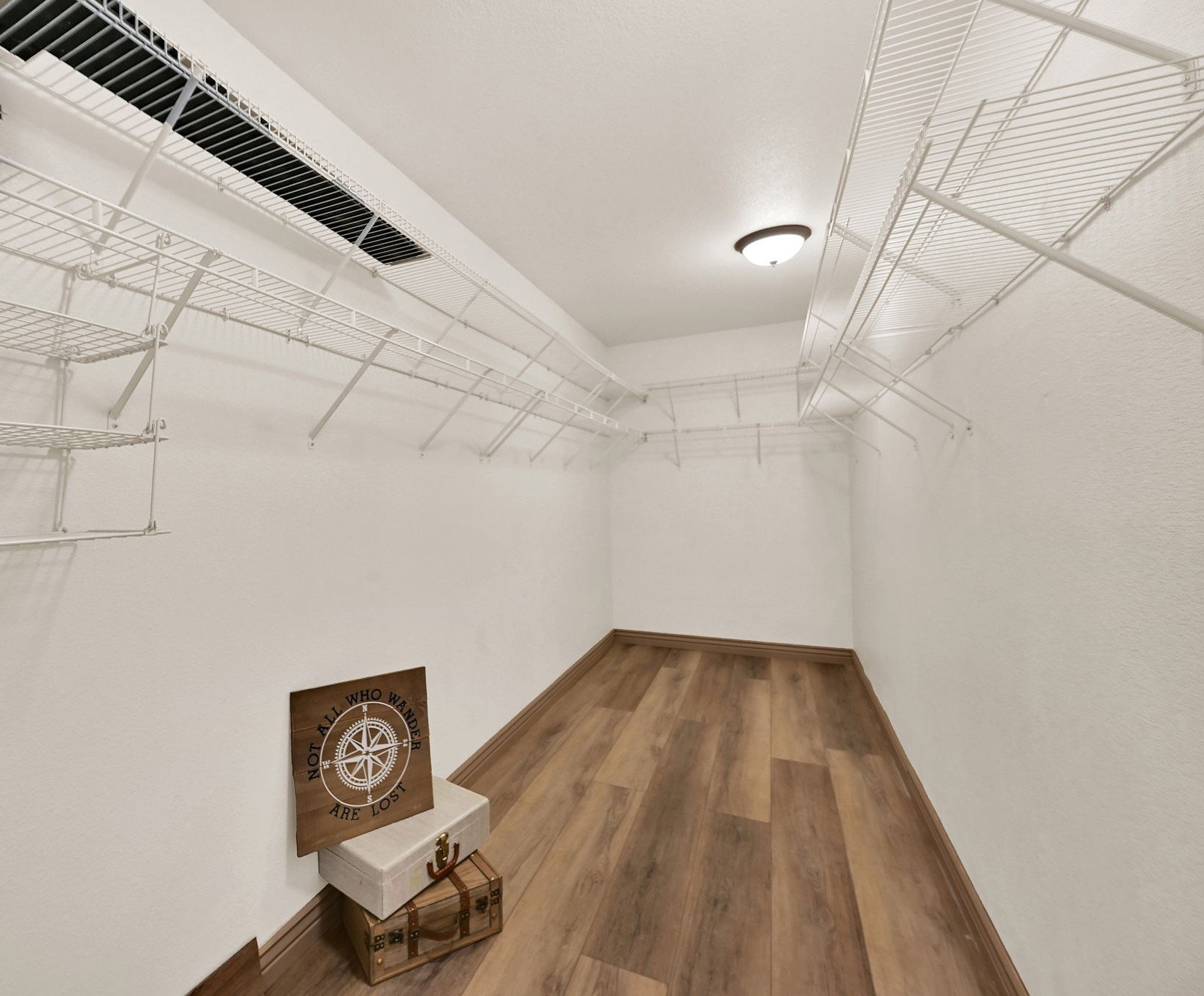 HUGE primary bedroom walk-in closet featuring wood-finish flooring, white wire shelving, recessed lighting, and a ceiling-mounted light fixture