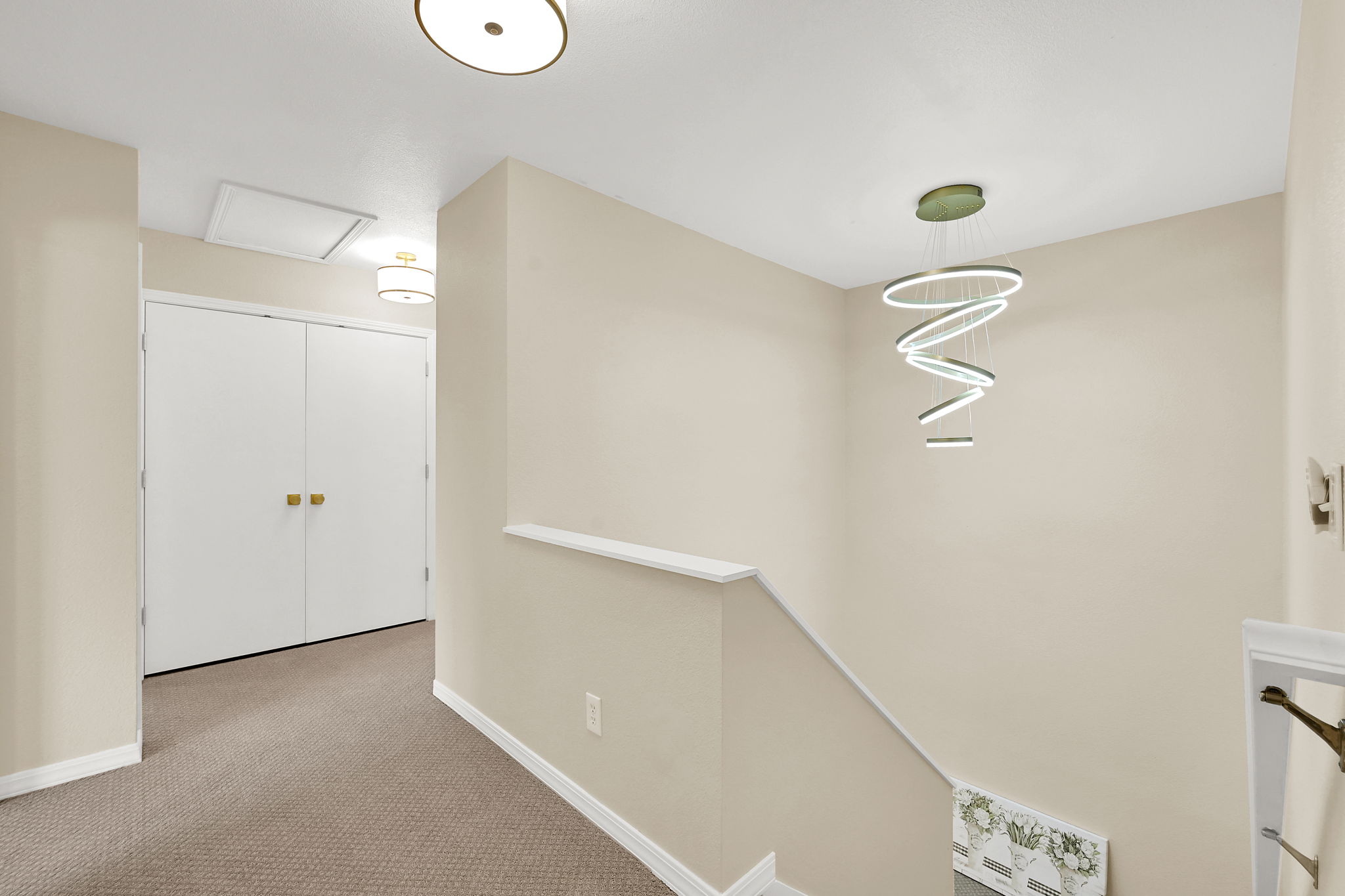 Hallway featuring a contemporary spiral chandelier, neutral wall paint, and modern ceiling lighting