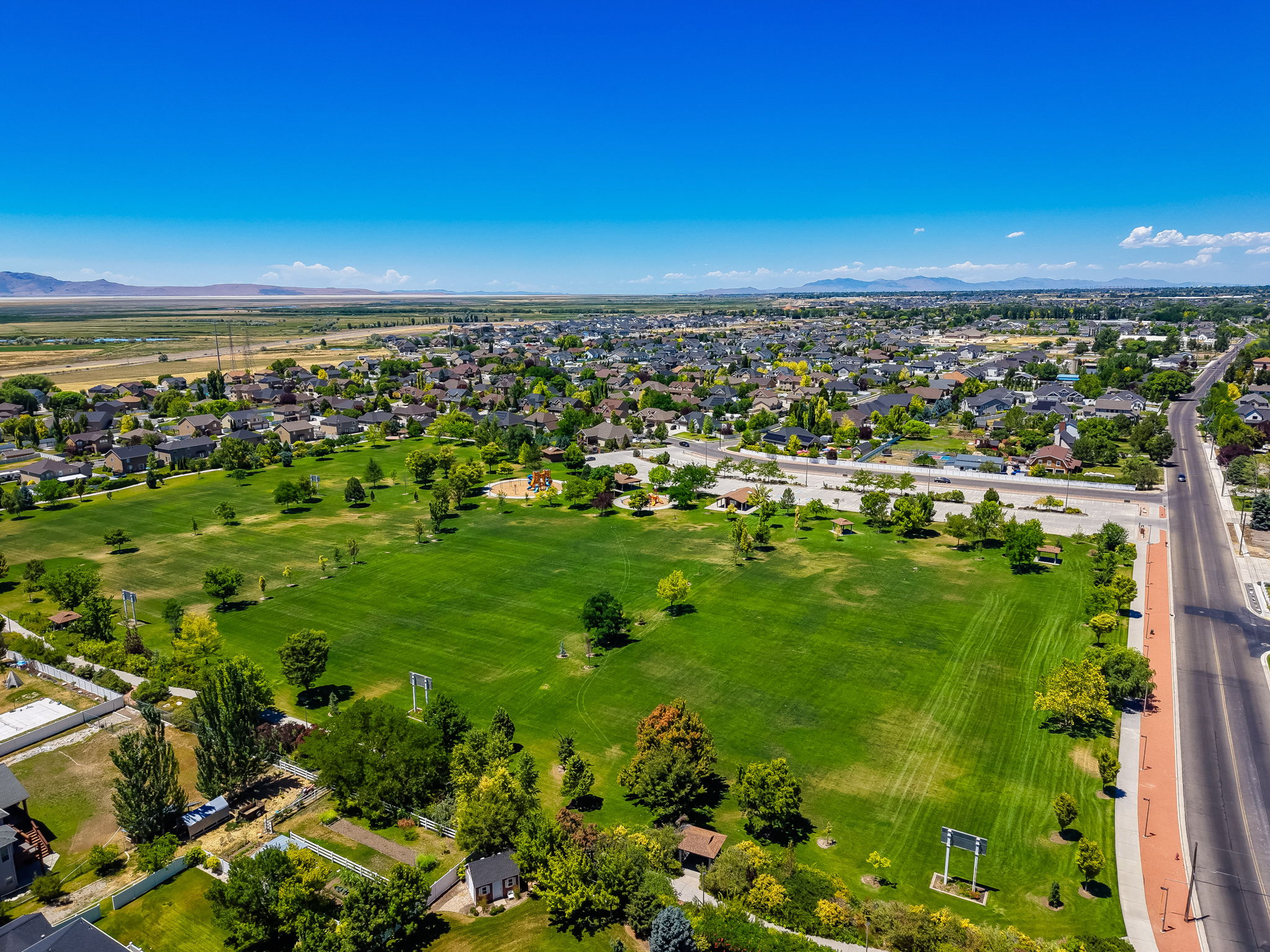 Angel Street Soccer Park within Steps Expansive green space featuring large grassy areas, mature trees, and recreational structures within a developed community setting