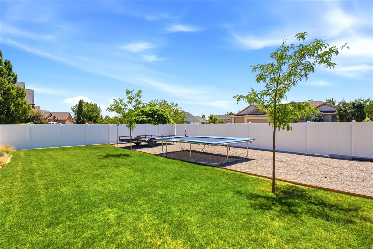 Expansive backyard featuring a green lawn, gravel area, and a privacy fence