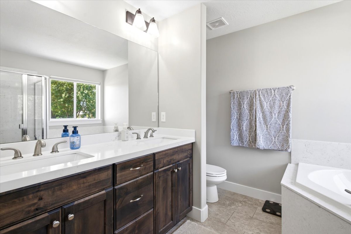 Dual sink vanity with dark wood-finish cabinetry and light-toned countertops