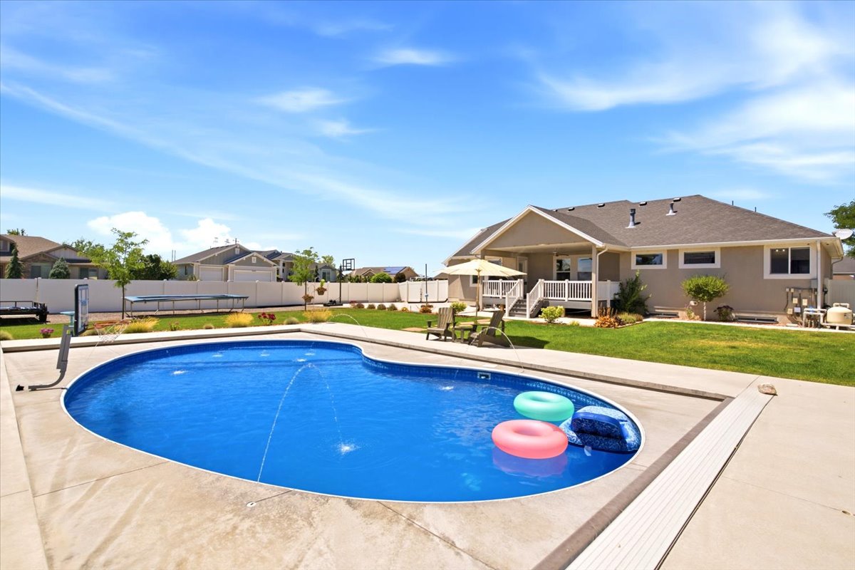 Expansive backyard featuring a freeform swimming pool with a concrete surround