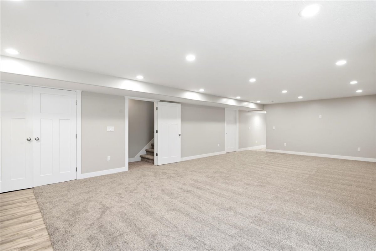 Spacious room featuring neutral carpeting, light gray walls, white trim, recessed lighting, and white paneled doors