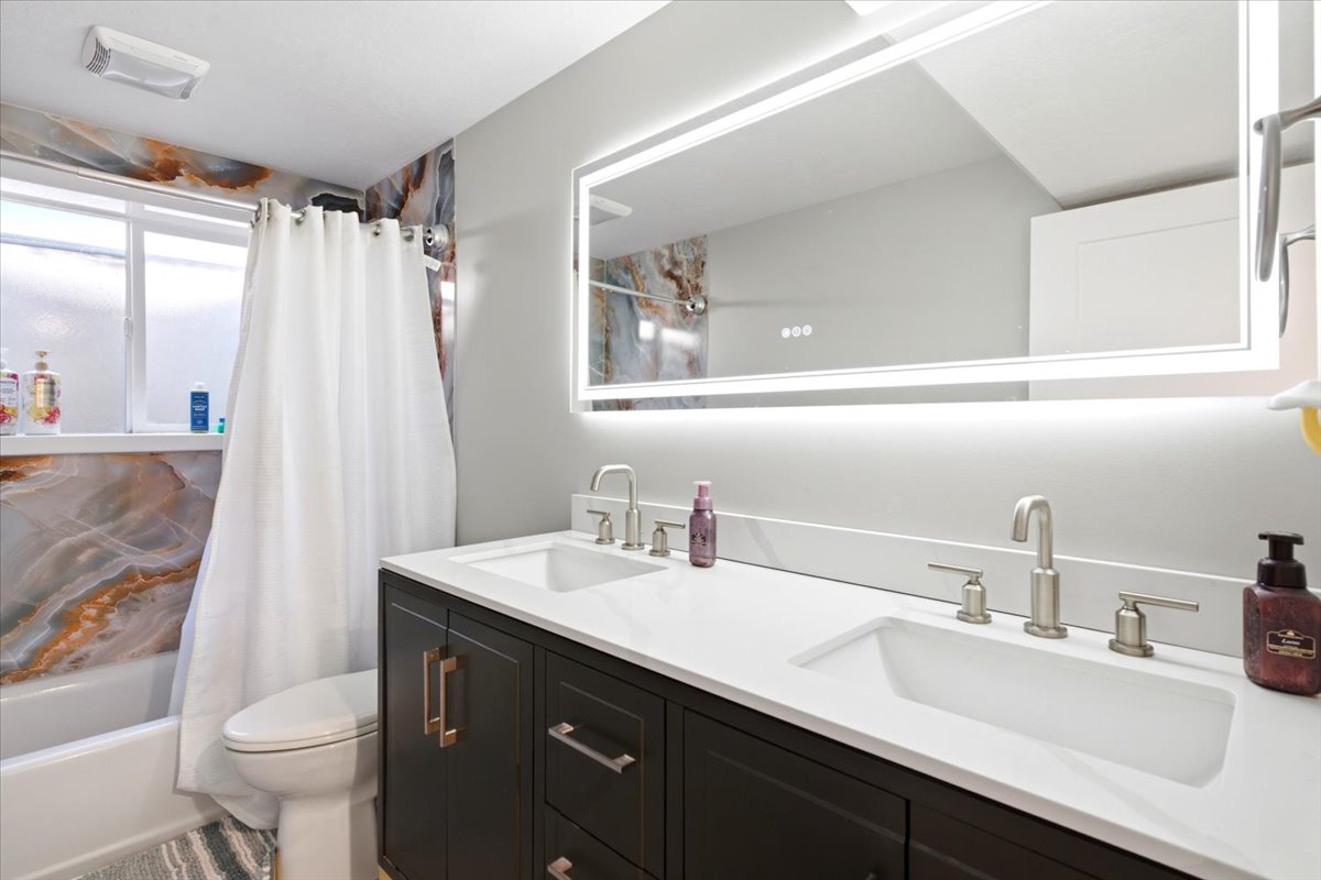 Dual vanity with integrated sinks, brushed nickel fixtures, a white countertop, and dark wood cabinetry