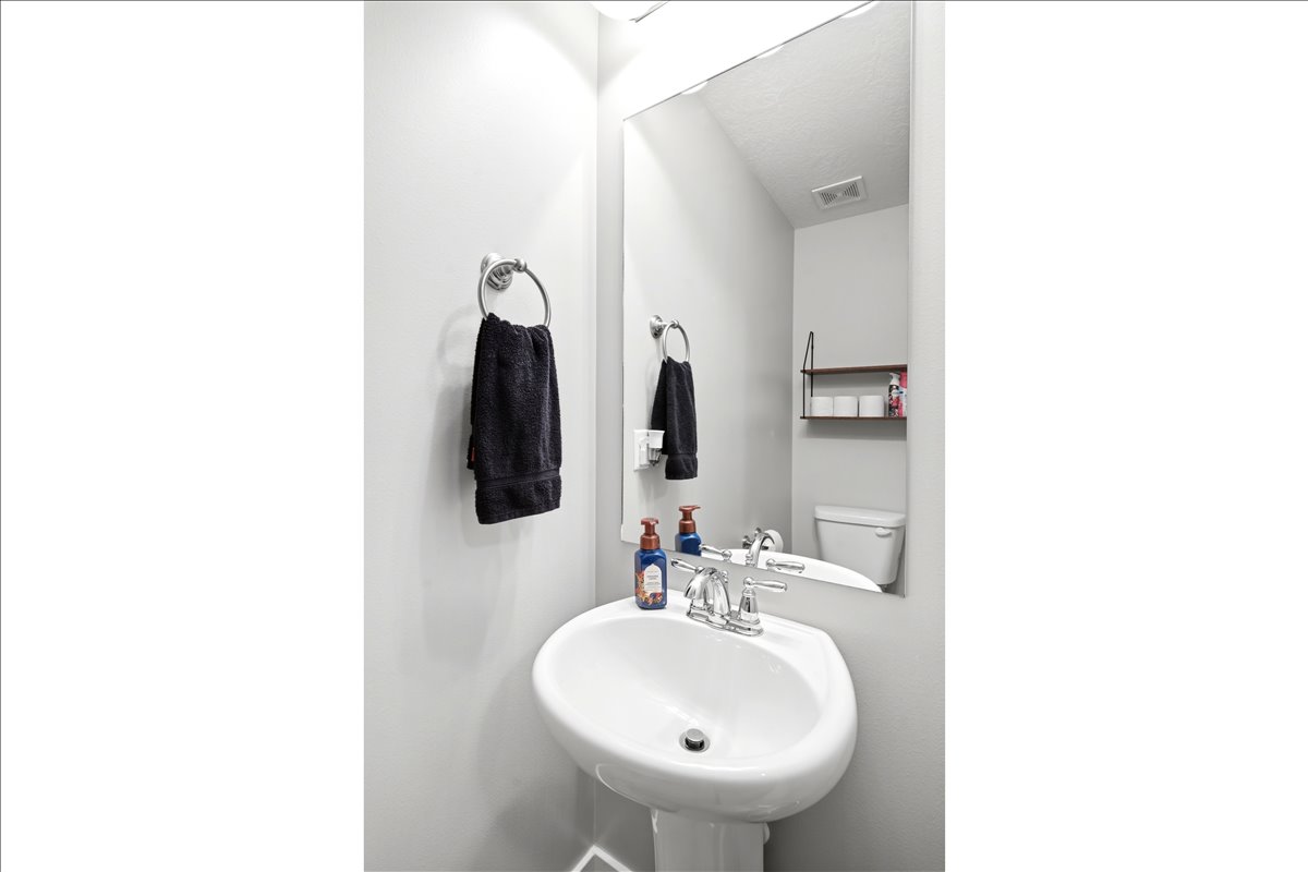 Pedestal sink with chrome faucet, large frameless mirror, and wall-mounted towel ring