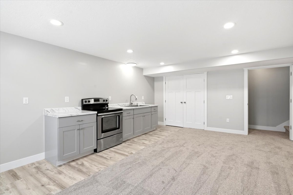 Kitchenette featuring a stainless steel range, light grey cabinetry, and stone-finish countertops