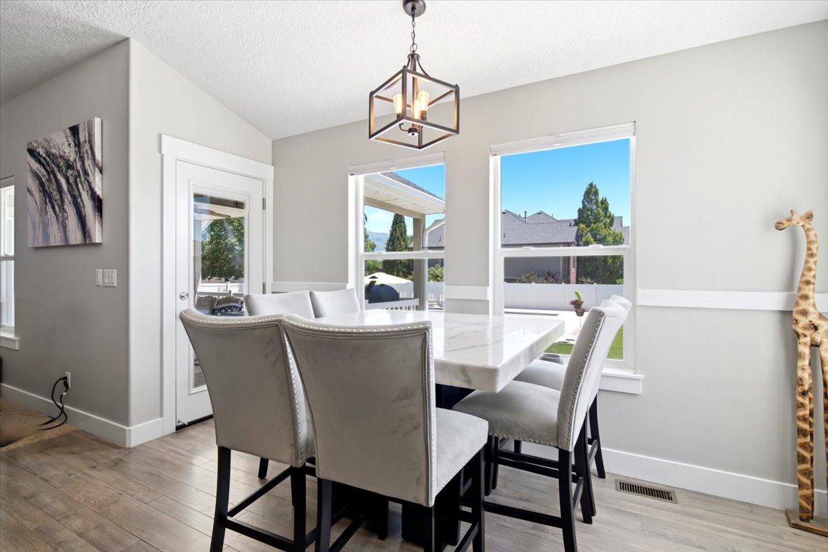 Dining area featuring wood-finish flooring, two large windows, a glass-paned exterior door, and a geometric pendant light fixture