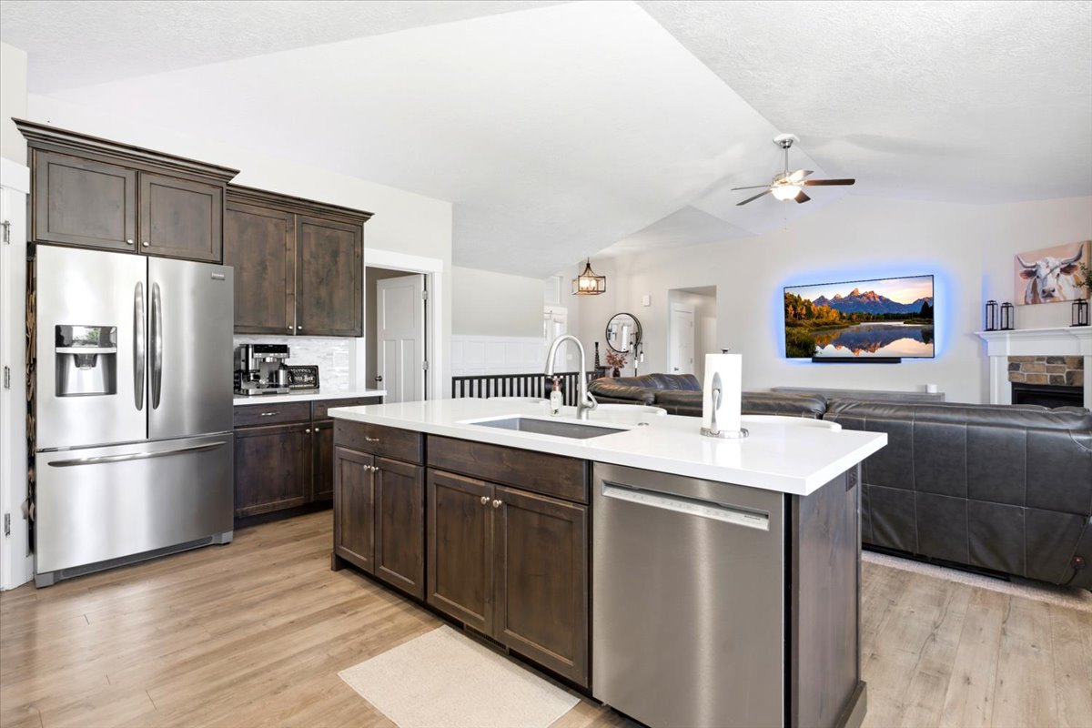 Kitchen featuring a large island with white countertop, dark wood-finish cabinetry, stainless steel appliances, and wood-finish flooring