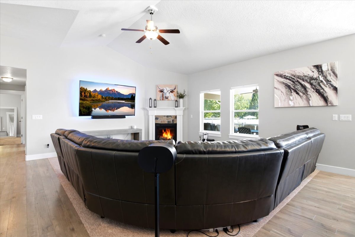 Living area featuring a fireplace with stone surround, a white mantle, and a wall-mounted television