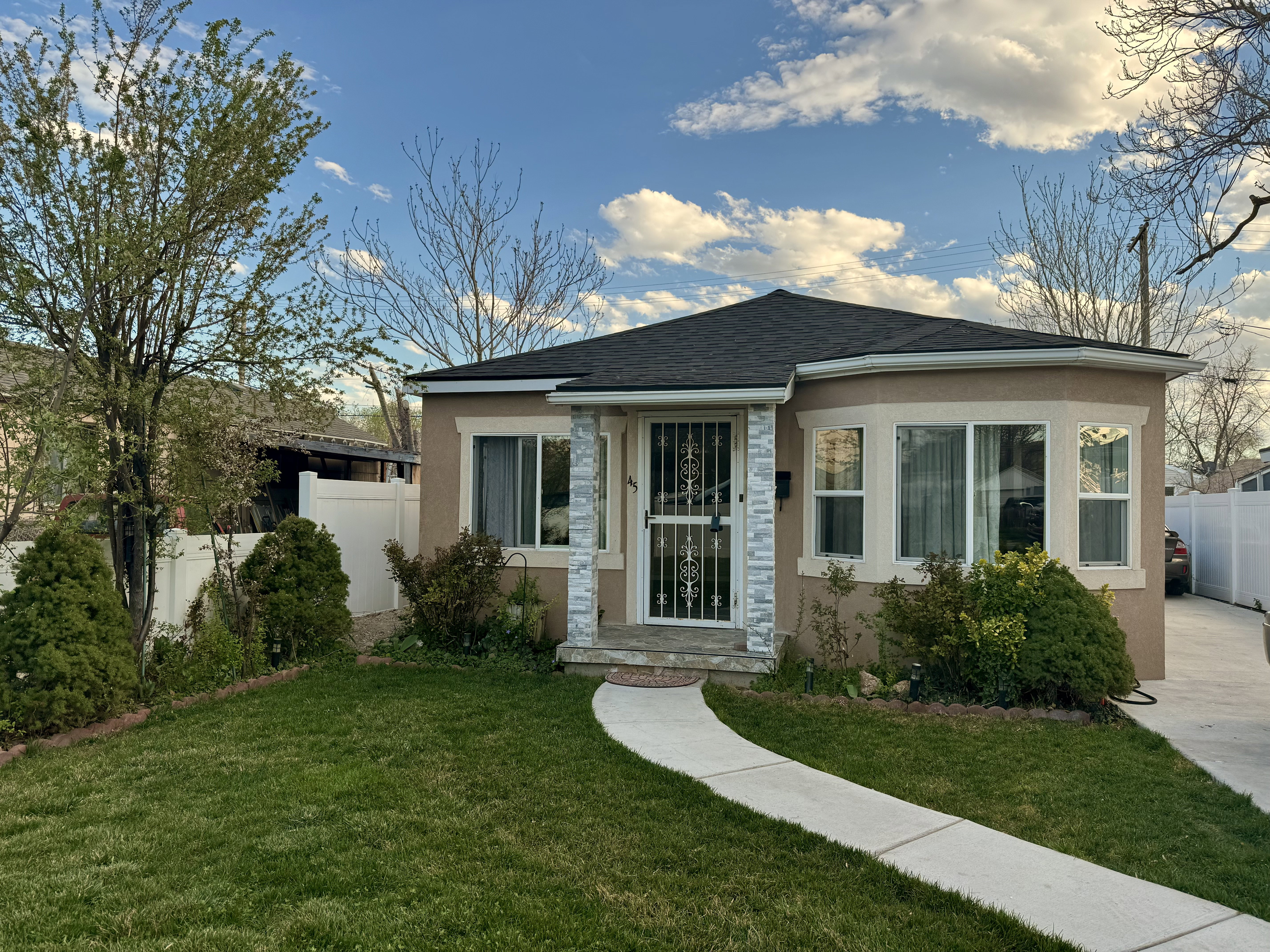 Stucco exterior with a dark shingle roof and a curved bay window