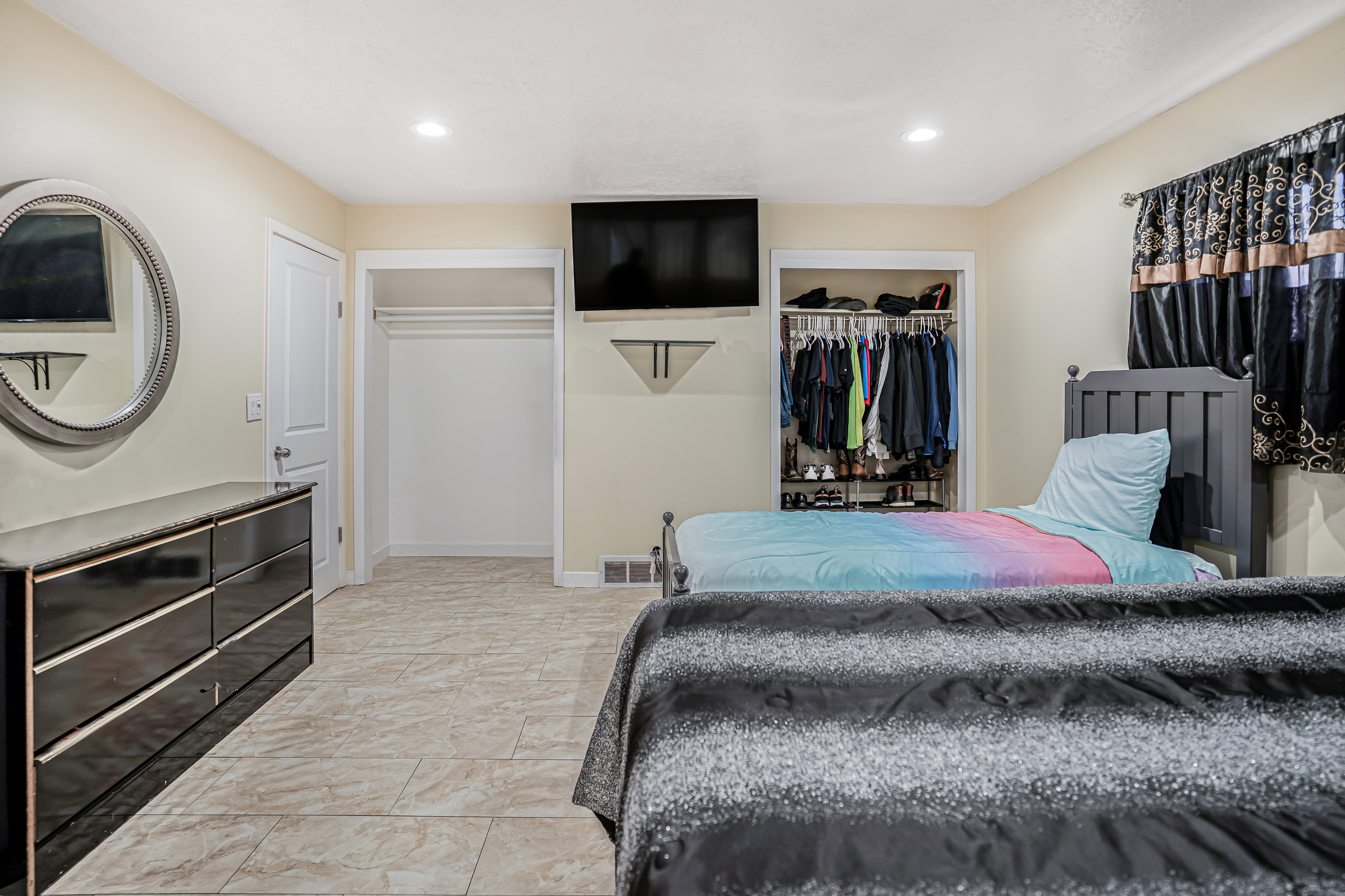 Bedroom featuring light-toned walls, recessed lighting, tile flooring, and a window with dark curtains