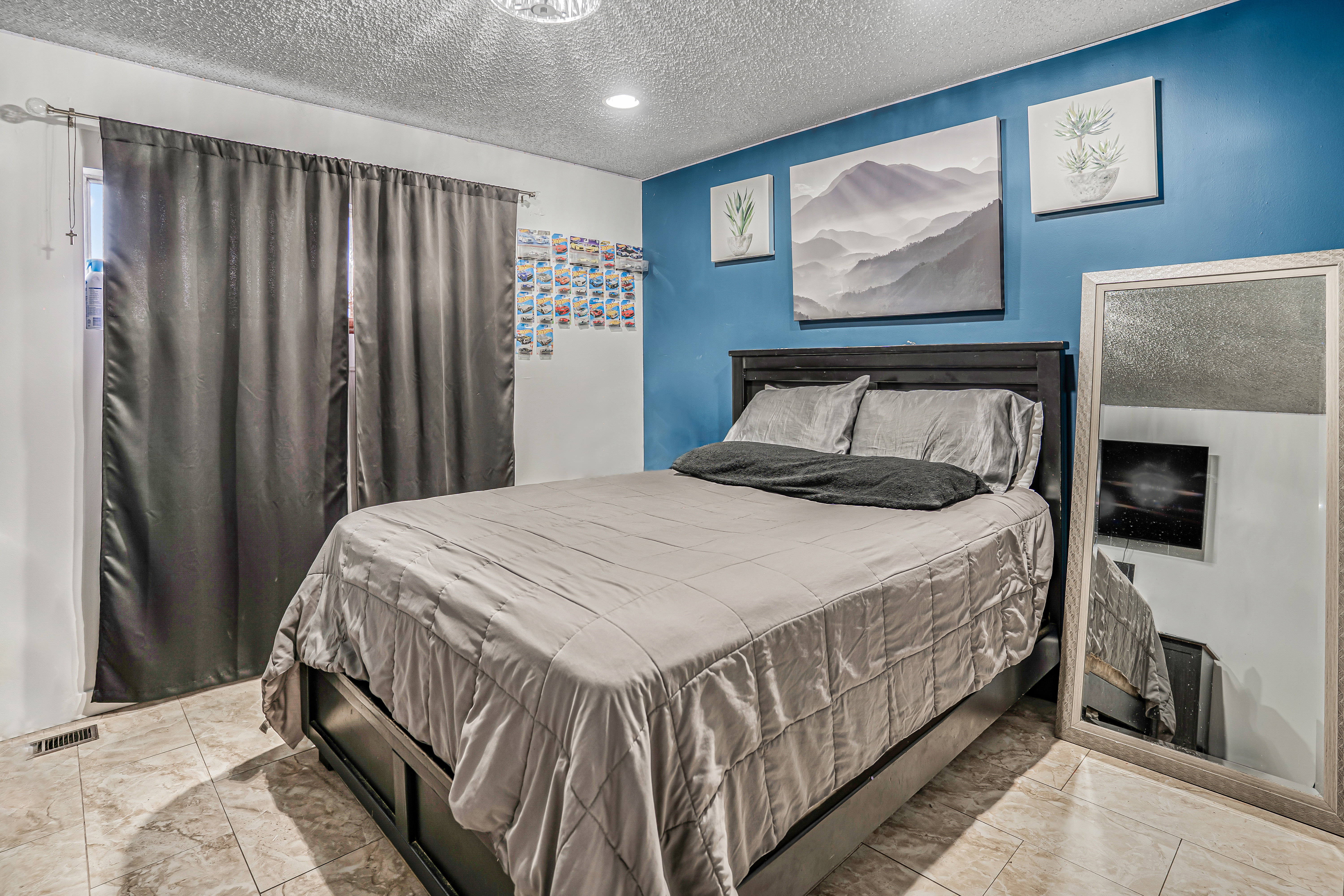Bedroom featuring tile flooring, a dark wood-finish bed frame, and a contrasting accent wall