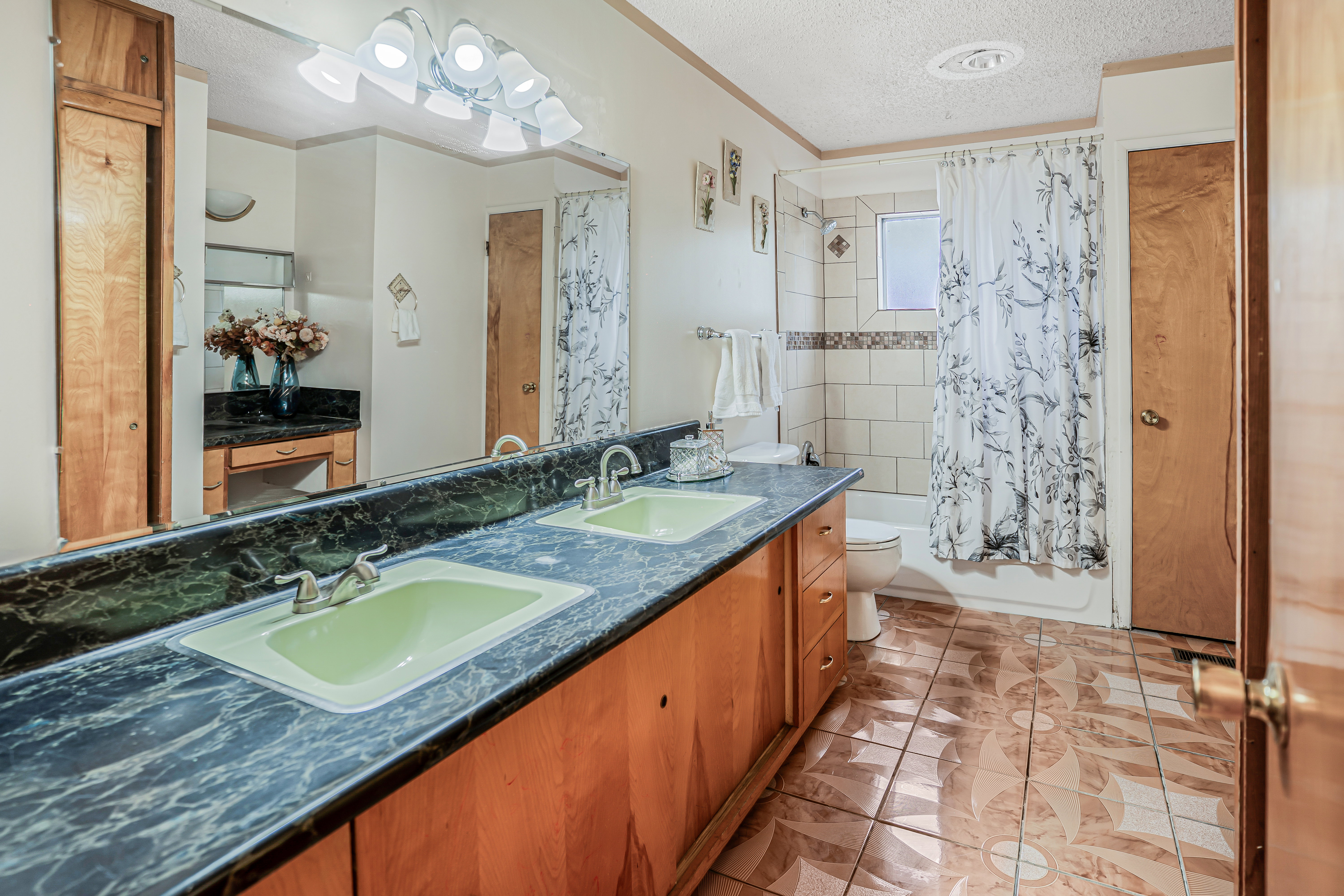 Dual vanity with integrated sinks, stone-look countertop, and wood-finish cabinetry