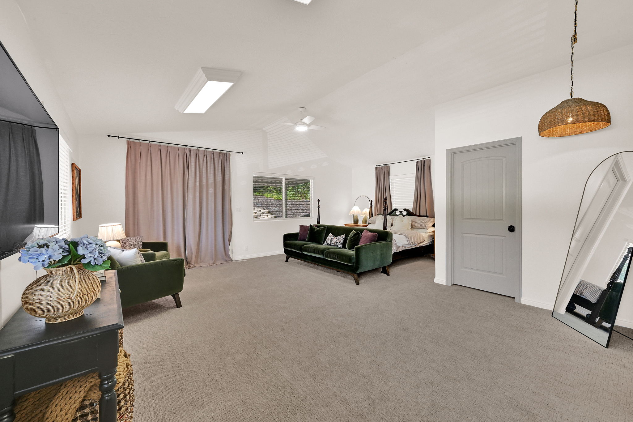 Spacious carpeted room featuring a ceiling fan, recessed lighting, and a light gray paneled door