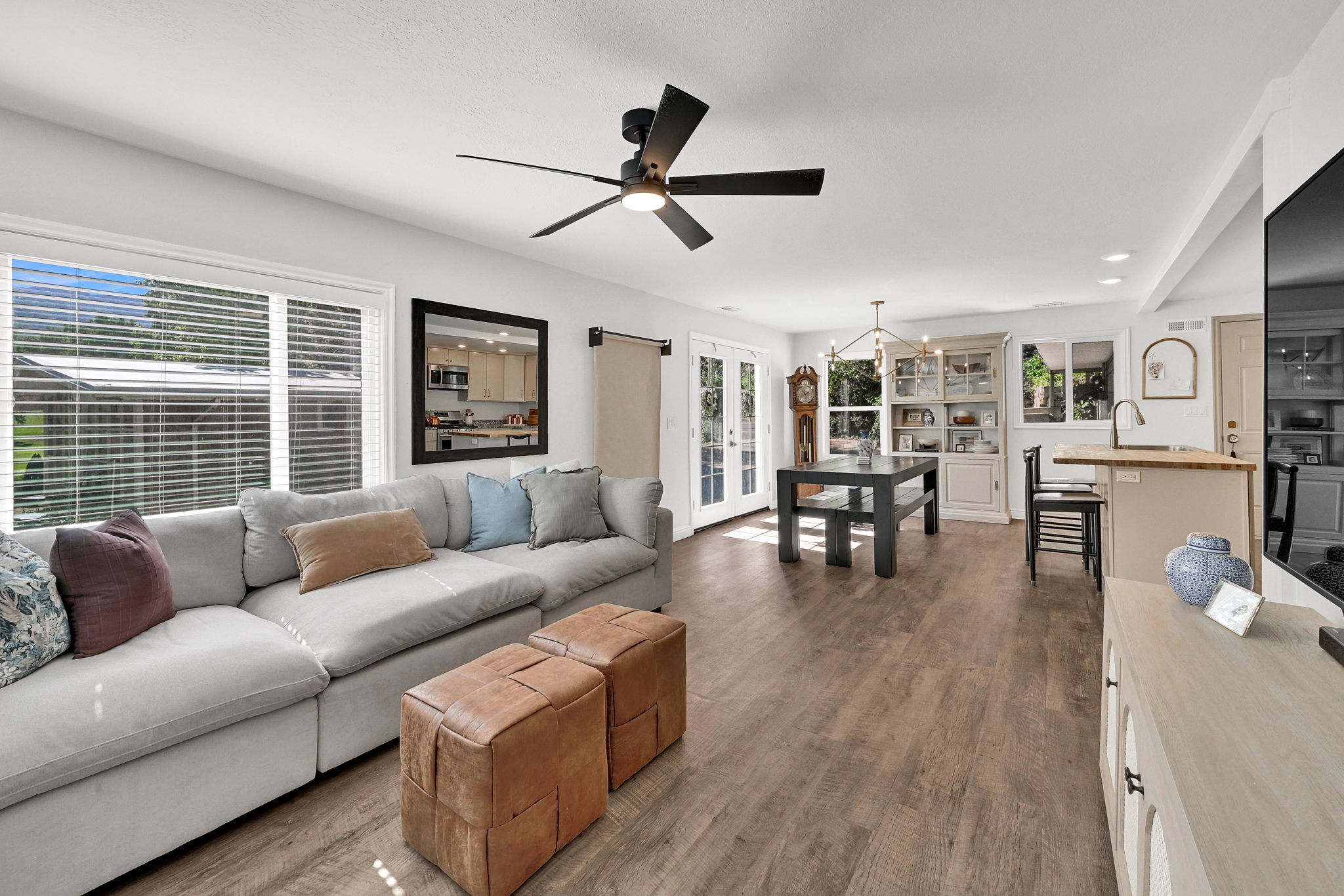 Open-concept living space featuring wood-finish flooring, a contemporary ceiling fan, and large windows with blinds