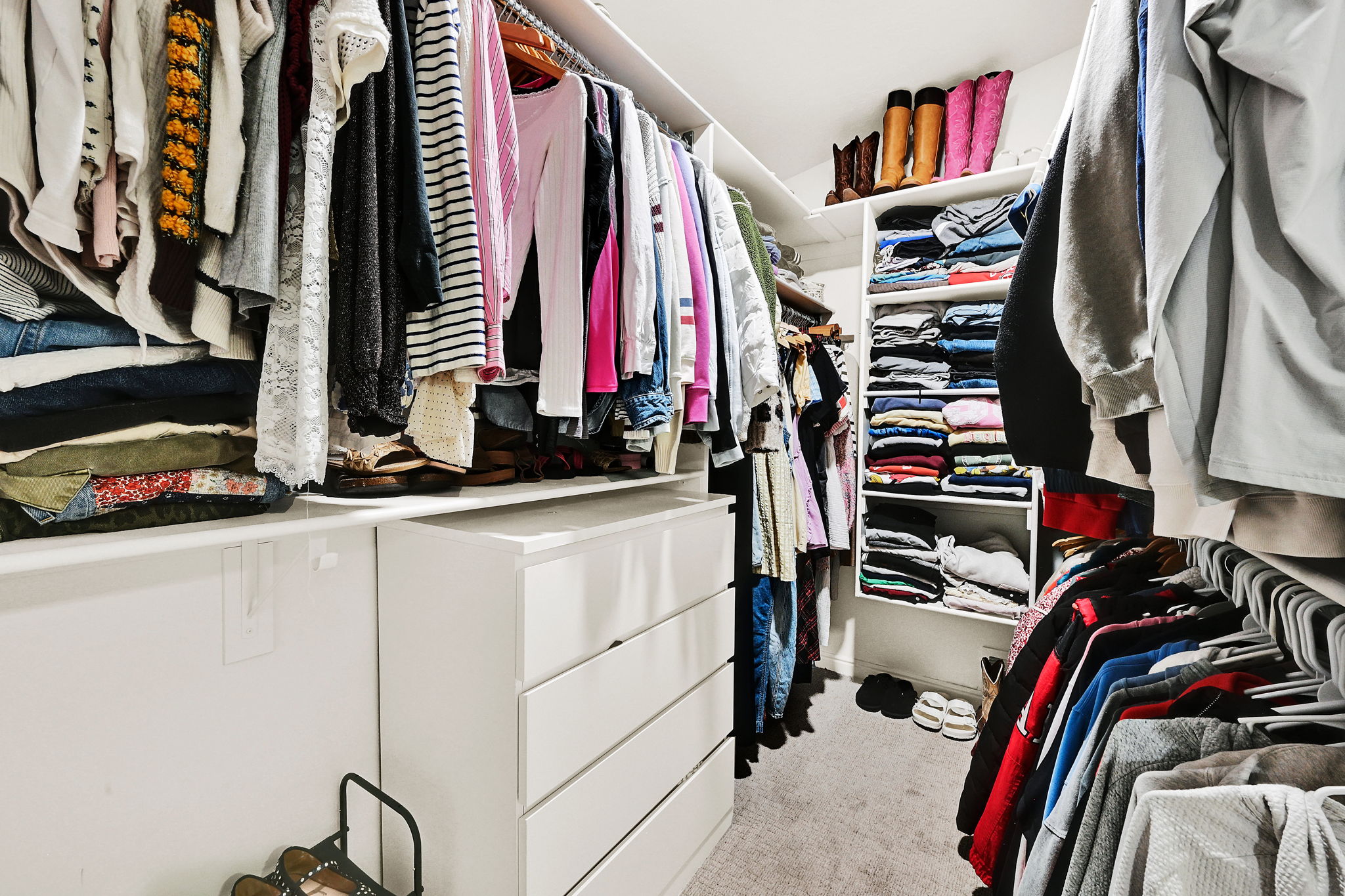 Custom owners suite built-in closet system featuring multiple hanging rods, integrated shelving units, and pull-out drawers in owners suite