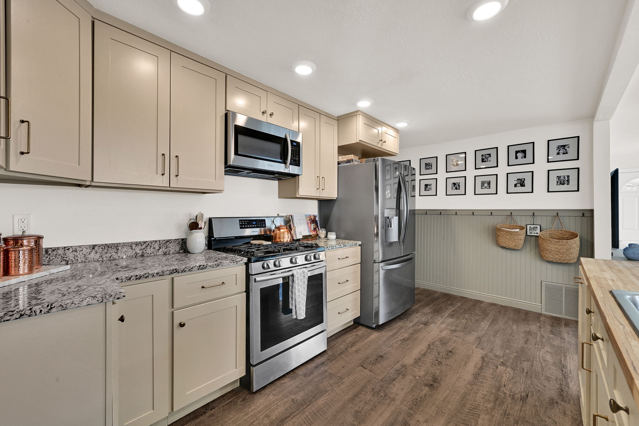 Kitchen featuring light-toned cabinetry, stainless steel appliances, speckled stone countertops, and wood-finish flooring