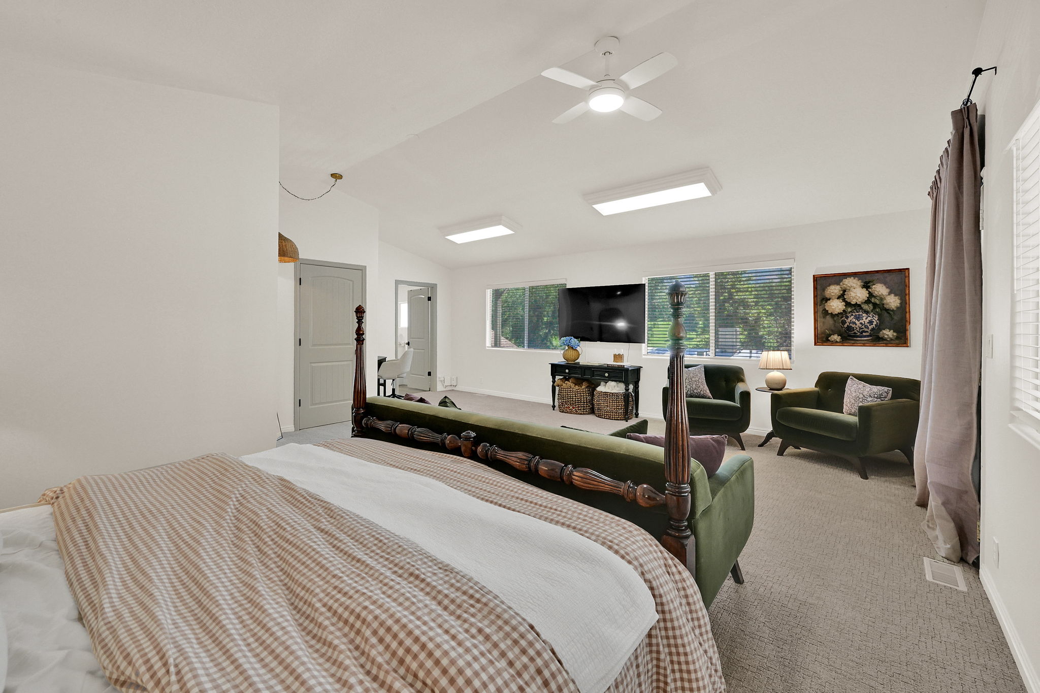 Spacious owners suite featuring vaulted ceilings, a ceiling fan with integrated lighting, recessed lighting, and multiple windows providing natural light