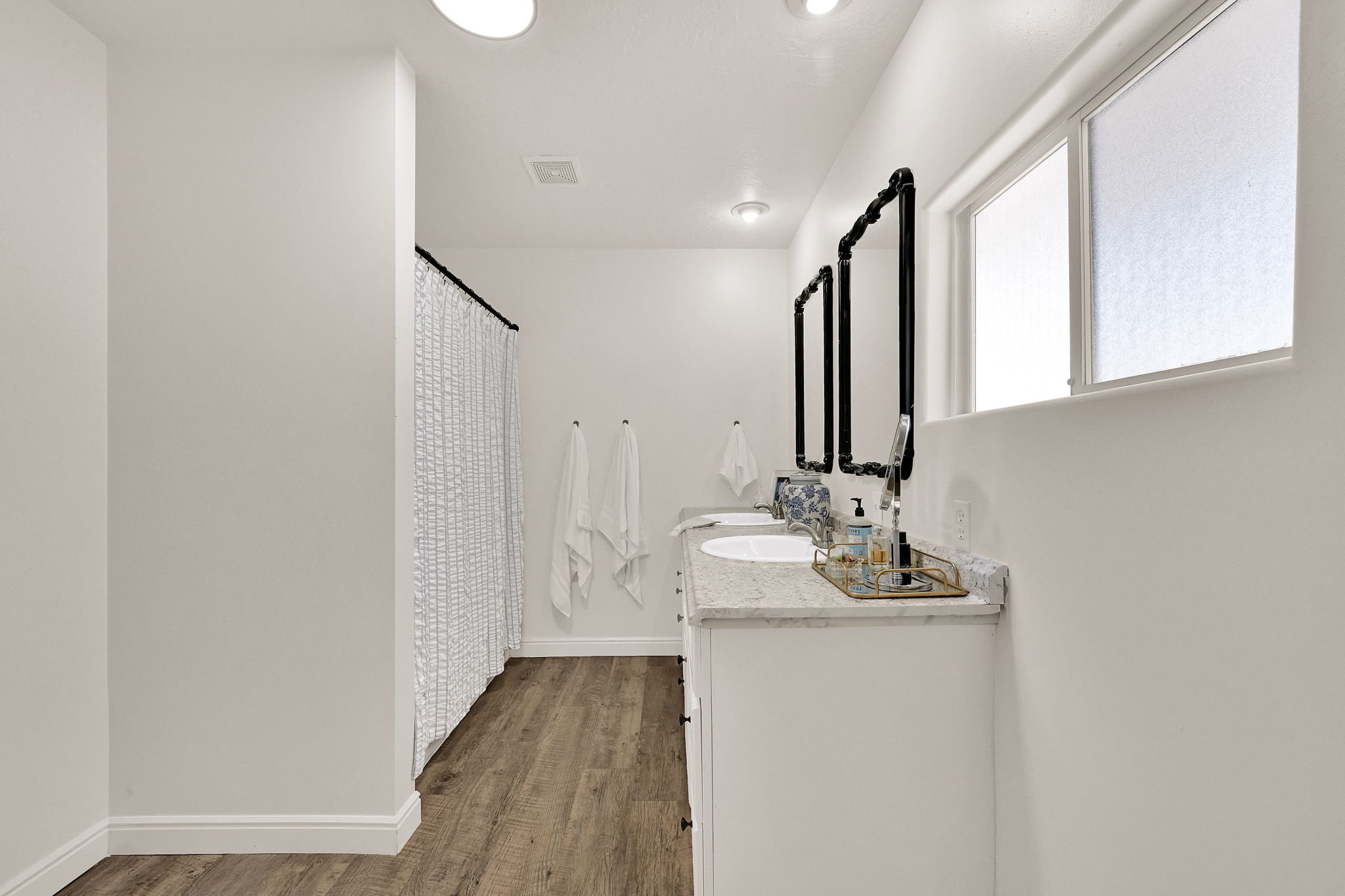 Owners ensuite featuring a double vanity with stone countertops, individual sinks, and black-framed mirrors